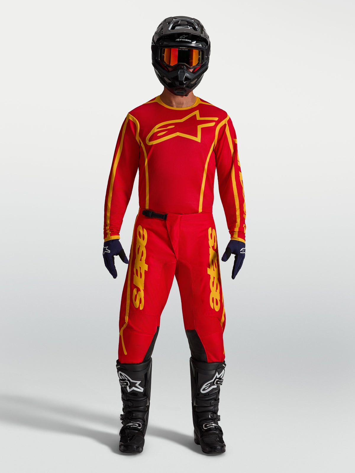 Alpinestars Fluid Apex V2 Trikot und Gear Set, Motocross-Bekleidung in Rot und Gold, Model in kompletter Rennausrüstung.