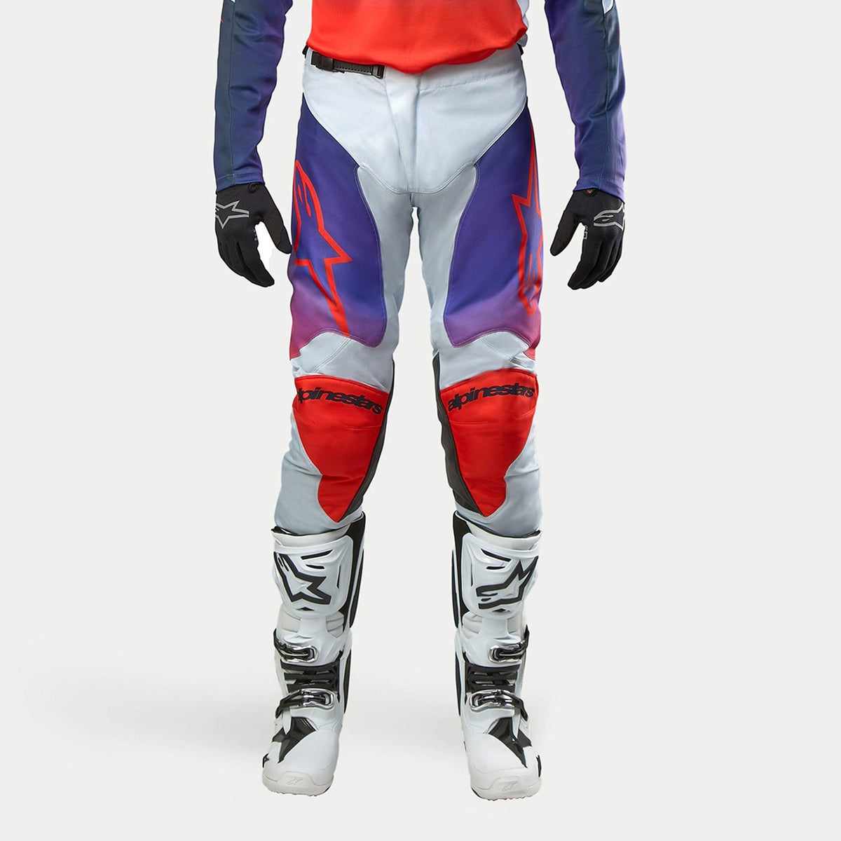 Alpinestars 2024 Racer Hoen Hose, Motocross-Hose, Hellgrau mit Hot Orange, Schwarz und Violett, ergonomisches Design, Teil einer Motocross-Ausrüstung mit weißen Stiefeln und schwarzen Handschuhen, Performance-Offroad-Bekleidung