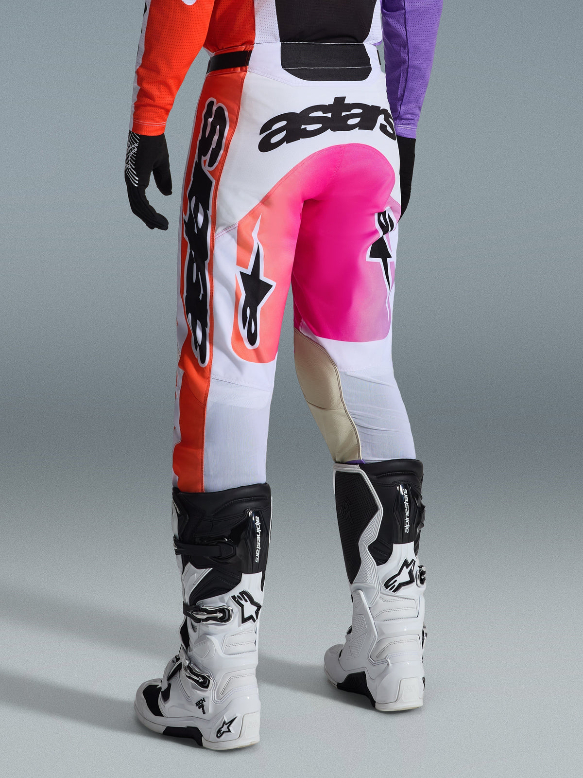 Alpinestars 2026 Racer Air Portl Pants, Motocross Pants, Multicolor with white, bright pink, and orange, rear view worn with white and black Alpinestars boots, featuring bold branding and durable racing construction