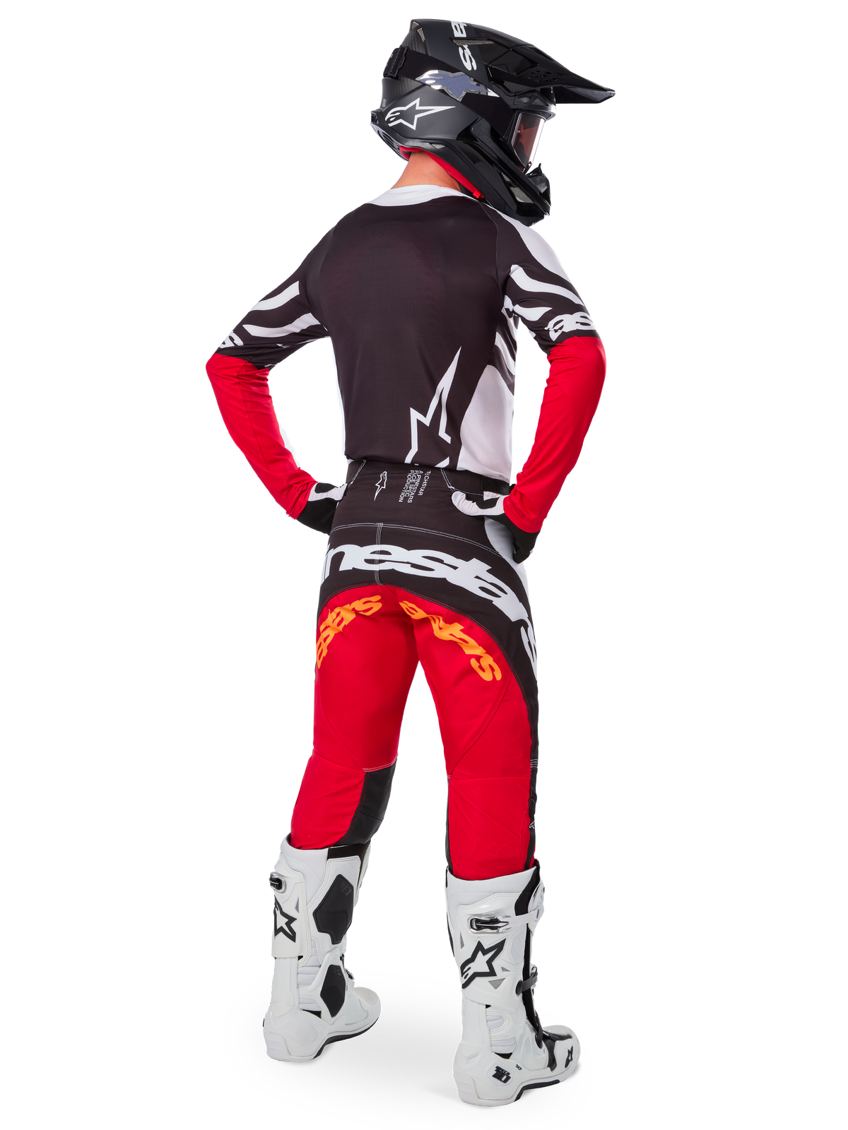 Rear view of a motocross rider wearing the Limited Edition Techstar Deep Gear Set, featuring a black jersey with white and red accents, matching red and black pants with 'Alpinestars' branding, white racing boots, and a black helmet, showcasing the complete off-road racing outfit.