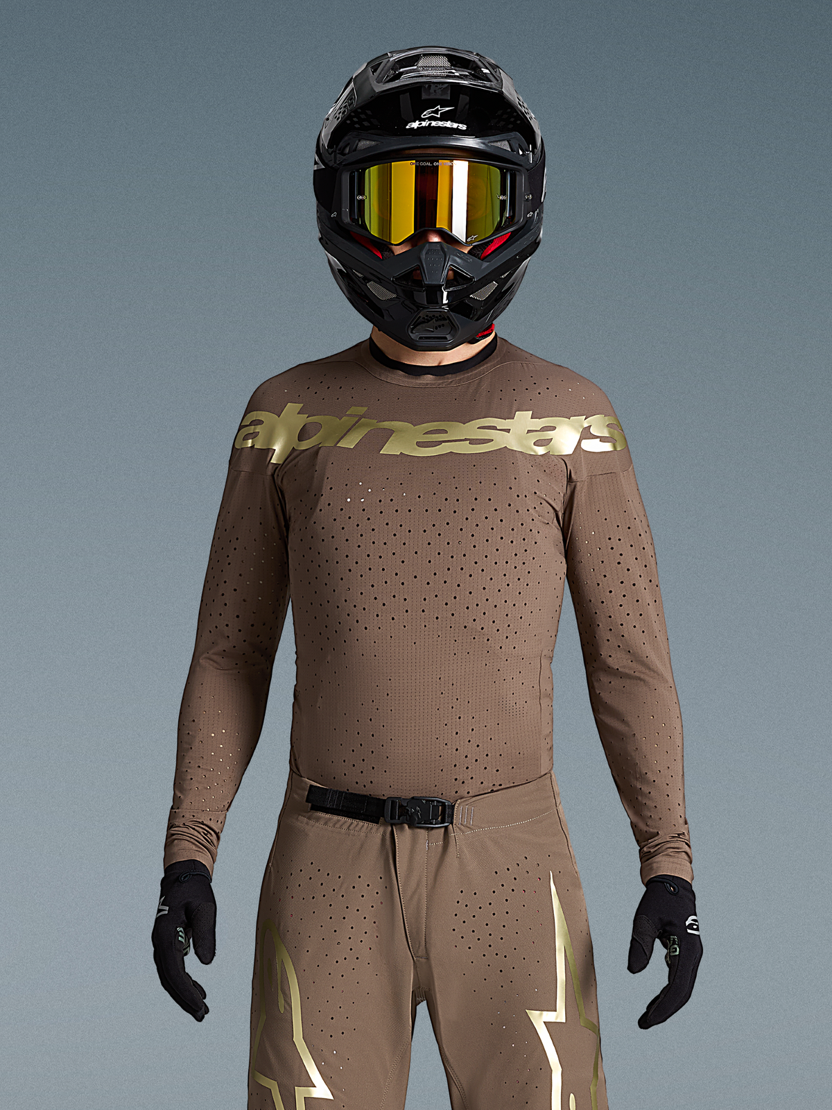 Alpinestars Limited Edition Supertech Air Gold Trikot, Herren-Motocross-Trikot, Braun und Gold, laser-geschnittene Belüftung, getragen mit Helm.