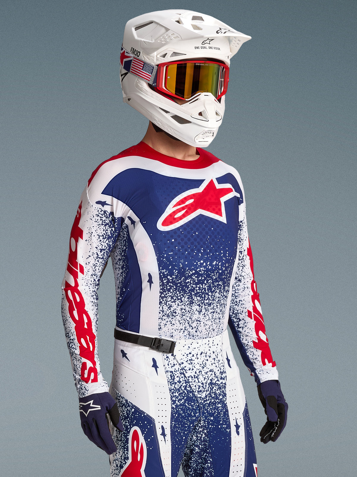 Alpinestars Limited Edition Techstar Unity Trikot, Motocross-Renntrikot für Herren, Rot und Blau mit Splatter-Design, am Model mit weißem Helm.