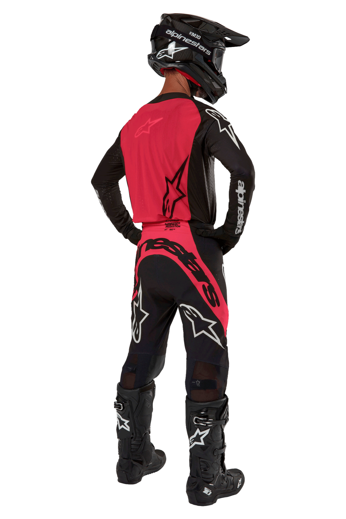 Motocross-Fahrer von hinten im 2024 Supertech Ward Jersey in Black Red Berry, mit leuchtend roter Rückenpartie und schwarzen Ärmeln mit weißem Alpinestars-Logo, kombiniert mit passender Motocross-Hose, schwarzen Tech 10 Stiefeln und einem schwarzen Carbonhelm, professionelles Rennsport-Ausrüstungsset.
