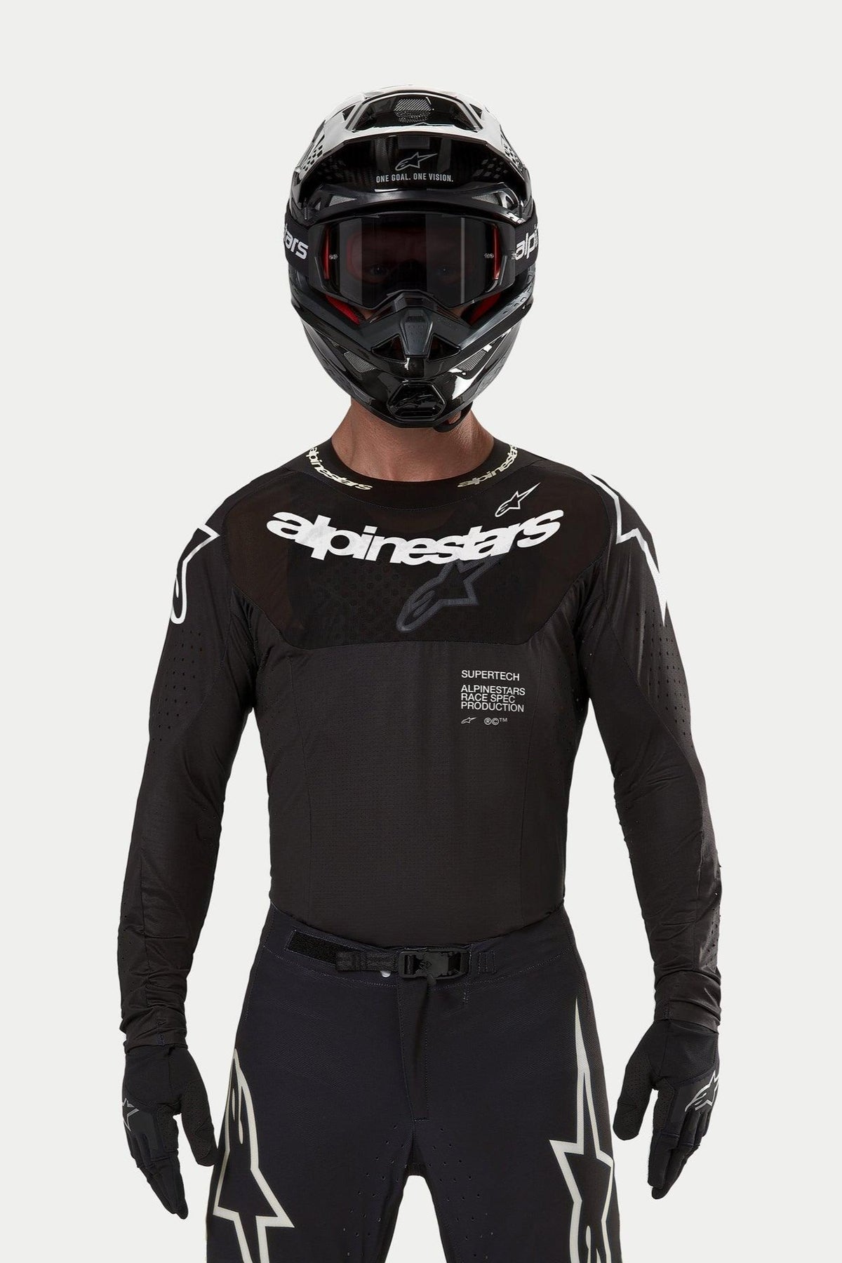 Motocross-Fahrer im Alpinestars 2024 Supertech Ward Jersey in Schwarz, athletische Rennpassform mit weißem Alpinestars-Logo auf der Brust, lasergeschnittenen Perforationen und 'Supertech Race Spec'-Schriftzug, kombiniert mit schwarzem Helm und Brille für den Offroad-Rennsport.