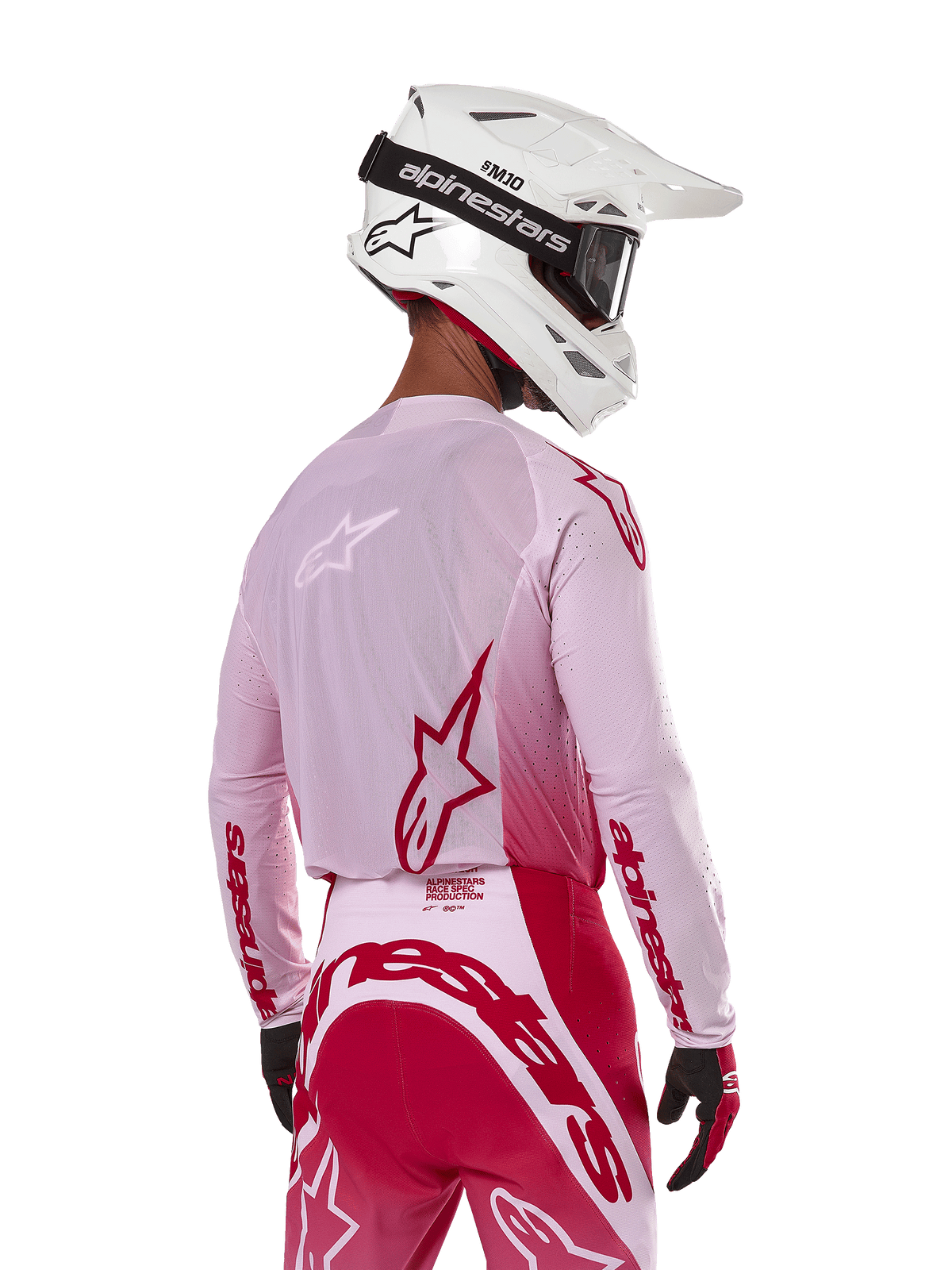 Motocross rider viewed from the back wearing the Alpinestars 2024 Supertech Dade Jersey in Red Berry Lilac, featuring breathable mesh panels and red Alpinestars logos, paired with matching red and lilac pants and a white Alpinestars helmet with goggles, professional off-road racing gear