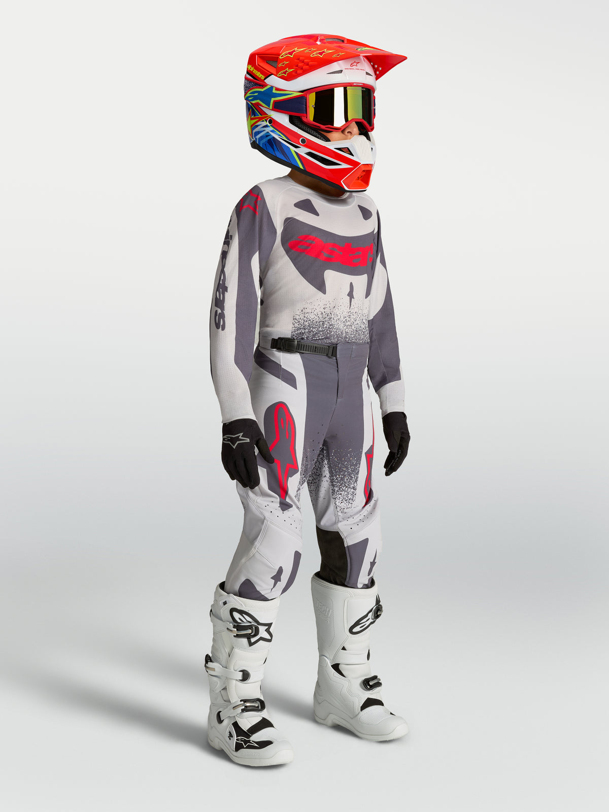 Alpinestars Youth Supertech Swan Jersey and Gear Set, gray and red fluo motocross outfit on-model with white racing boots.