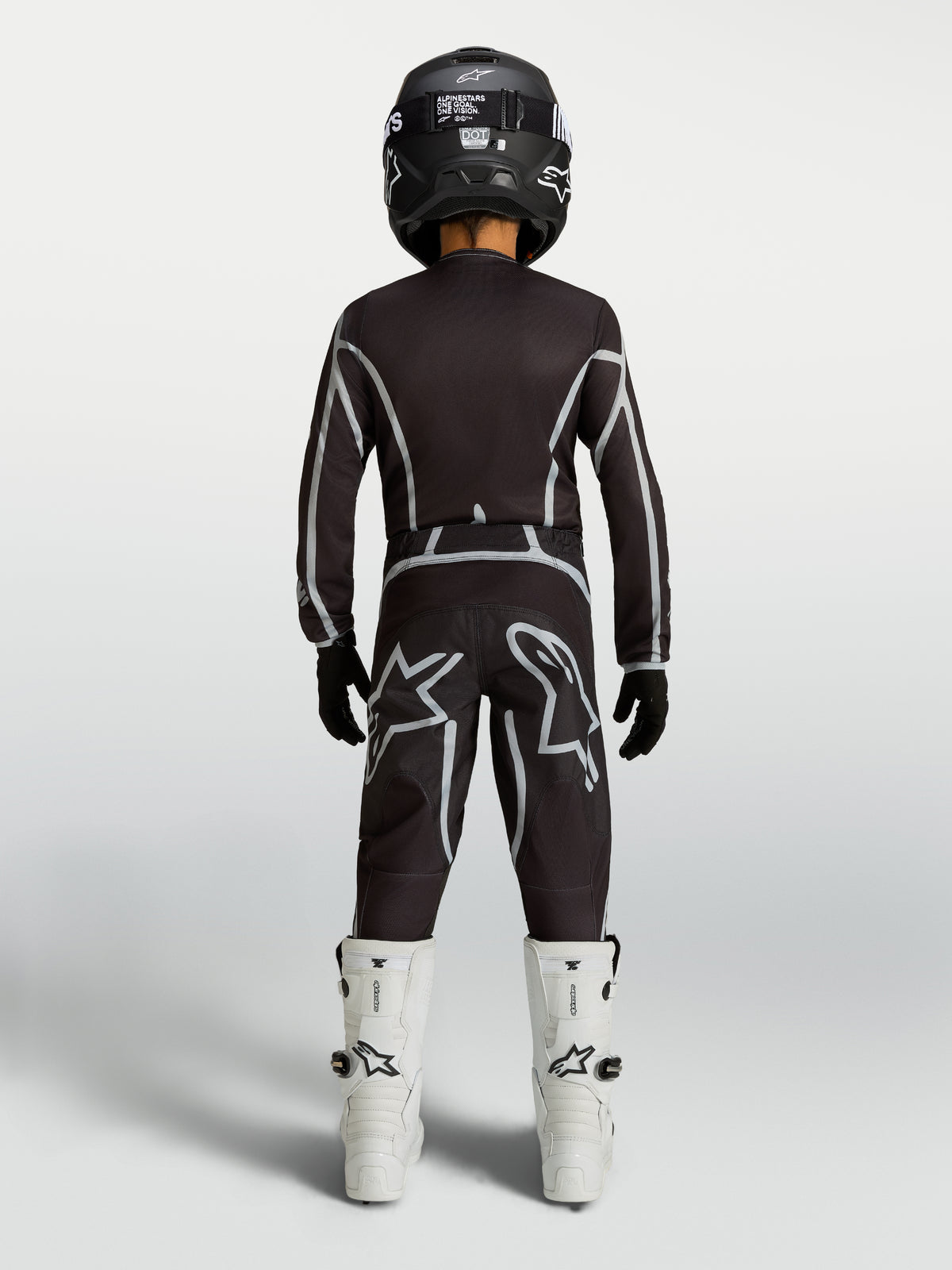 Alpinestars Fluid Apex V2 Jugend-Trikot und Gear Set, Motocross-Kombi in Schwarz und Silber, weiße Stiefel, Rückansicht.
