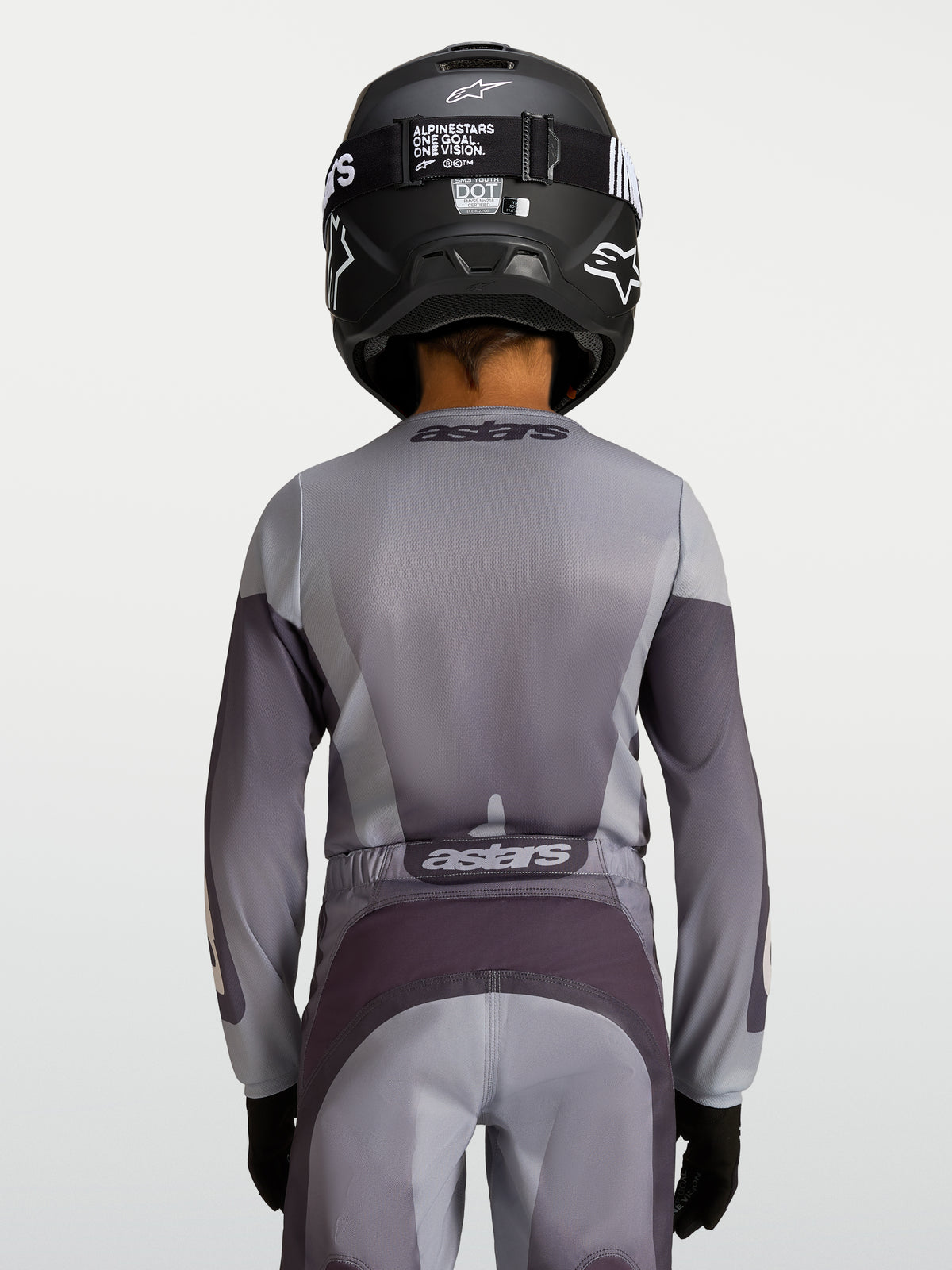 Alpinestars Fluid Jugend-Trikot Amber 2027, Motocross-Trikot für die Jugend, Sand und Grau, atmungsaktives Polygewebe, Rückansicht eines jungen Fahrers mit Helm.