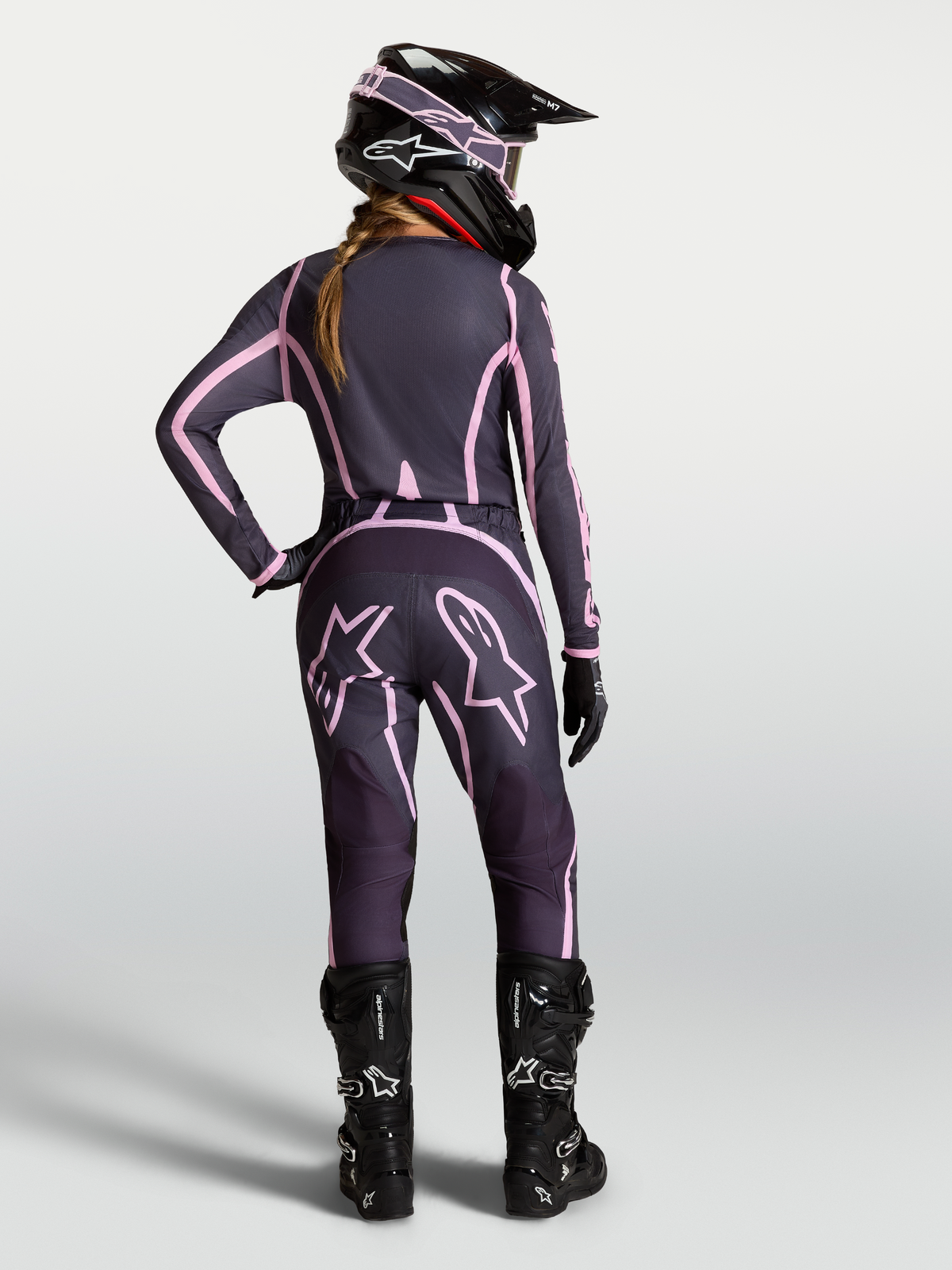Alpinestars Stella Fluid Apex V2 Hose, Damen-Motocrosshose in Grau und Pink, Rückansicht einer Fahrerin mit kompletter MX-Ausrüstung, ergonomische Passform für Offroad-Einsätze