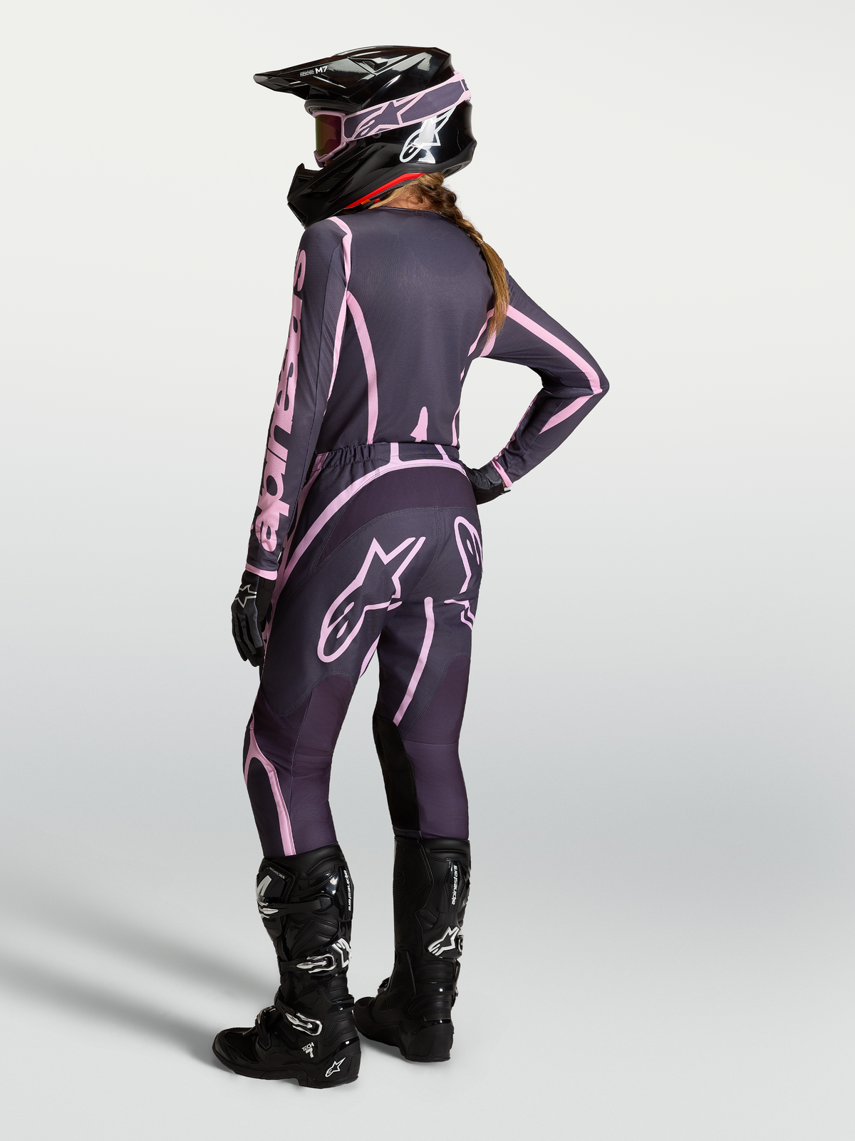 Alpinestars Stella Fluid Apex V2 Hose, Motocross-Hose für Damen in Grau und Pink, Rückansicht einer kompletten Offroad-Ausrüstung mit Trikot, Tech 7 Stiefeln und Helm.
