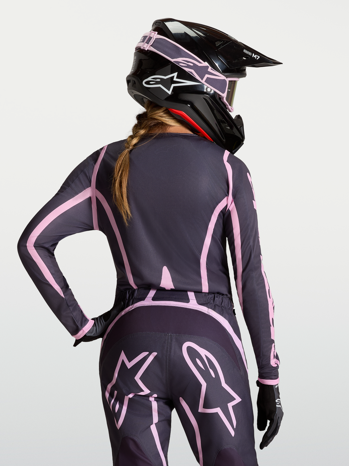 Alpinestars Stella Fluid Apex V2 Trikot, Damen-Motocross-Jersey in Grau und Rosa mit verlängerter Rückenpartie, am Modell getragen mit passendem Helm
