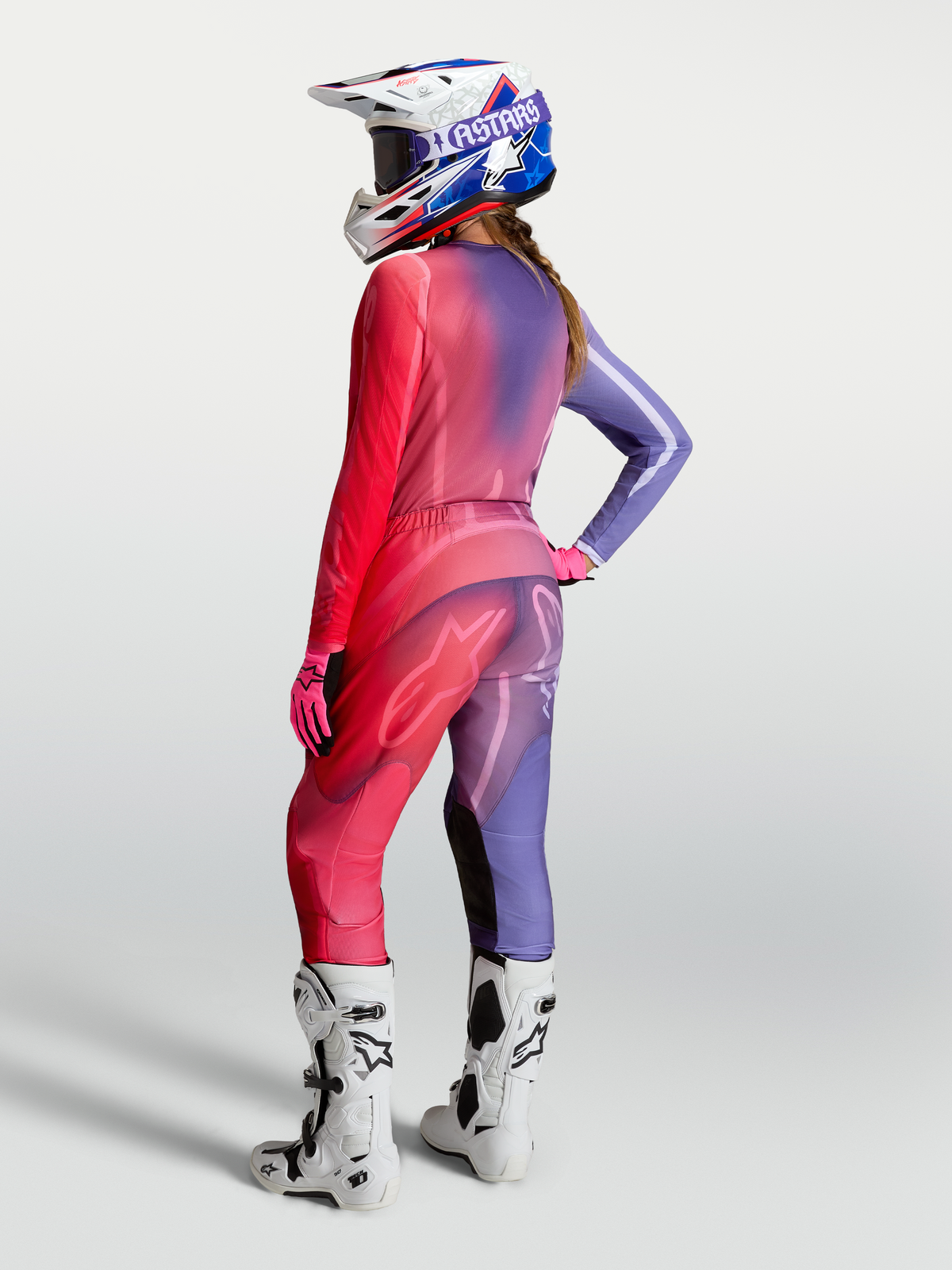 Alpinestars Stella Fluid Kepler Trikot, Damen-Motocross-Trikot in Lila und Rot, Rückansicht am Model mit passender Hose, Helm und Stiefeln.
