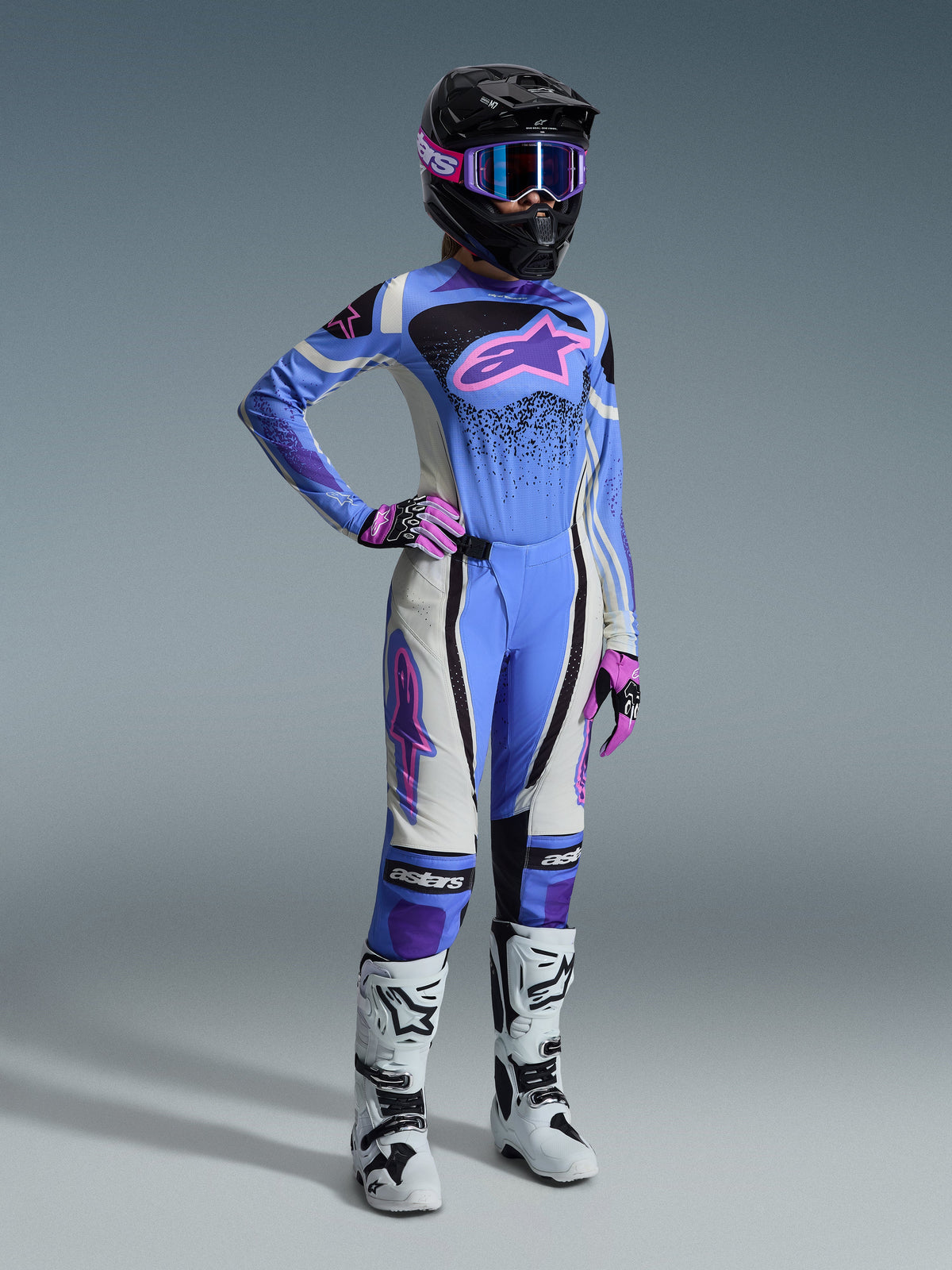 Alpinestars 2026 Stella Techstar Nomur Gear Set, Women's motocross gear featuring light blue jersey with pink Astar logo, matching pants with white and black paneling, black helmet with pink and purple goggles, pink gloves, and white motocross boots