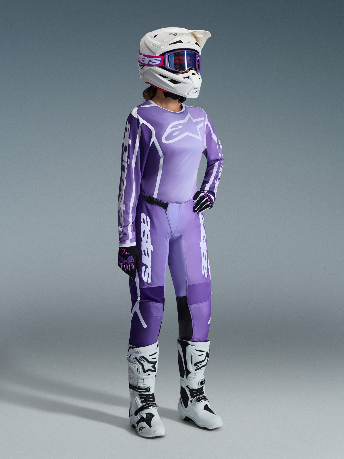 Alpinestars 2026 Stella Fluid Apex Gear Set, Lila und Lavendel, Motocross-Fahrerin in passendem Trikot und Hose, weißer Helm mit lila Brille, weiß-schwarze Stiefel, schwarz-lila Handschuhe, komplette Performance-Ausrüstung für Offroad-Rennen für Damen