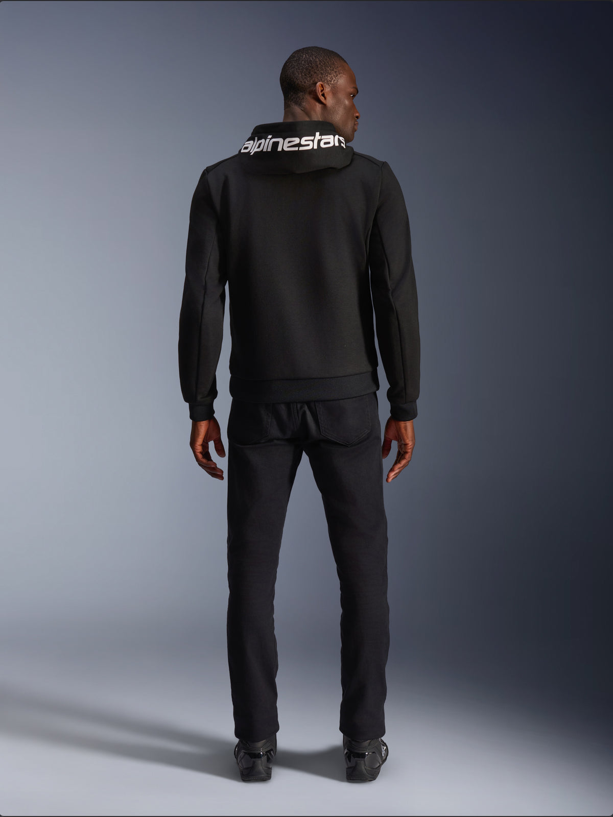 Alpinestars Chrome V2 Sport Kapuzenjacke, Motorrad-Hoodie, Schwarz, Tech-Fleece, Rückansicht am Model mit weißem Kapuzenlogo.