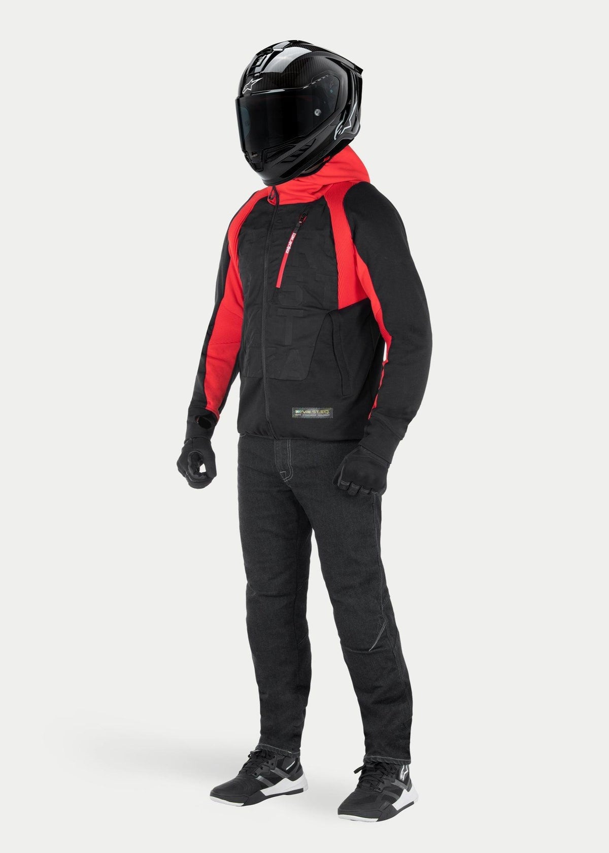 Alpinestars MO.ST.EQ Hybrid Kapuzenjacke in Black Flame Red, urbaner Motorrad-Hoodie mit roter Kapuze und Schulterakzenten, kombiniert mit schwarzem Integralhelm und Motorradhose, modernes Streetwear-inspiriertes Design