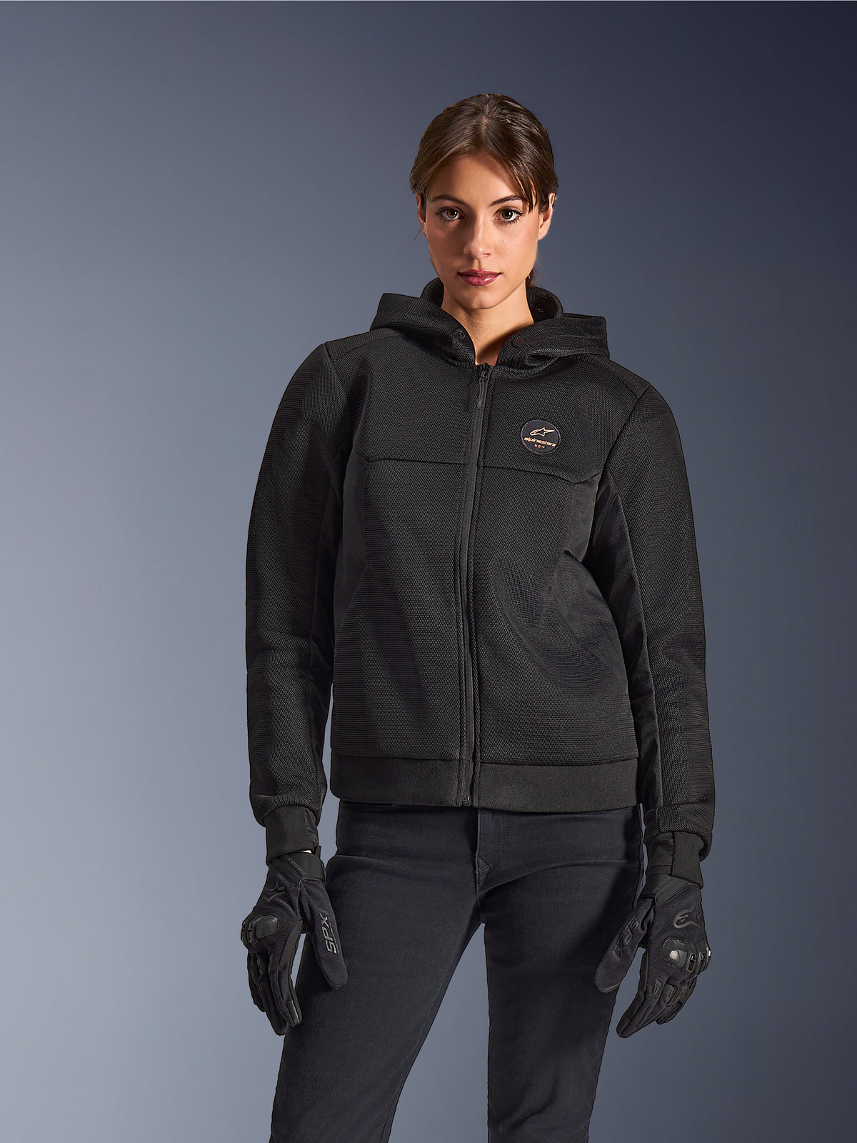 Alpinestars Stella Chrome Superairflow Hoodie, Damen-Motorrad-Hoodie, Schwarz, Kapuzenjacke mit Brustlogo und Frontreißverschluss, getragen mit schwarzen Handschuhen, modernes Design für urbanes Fahren