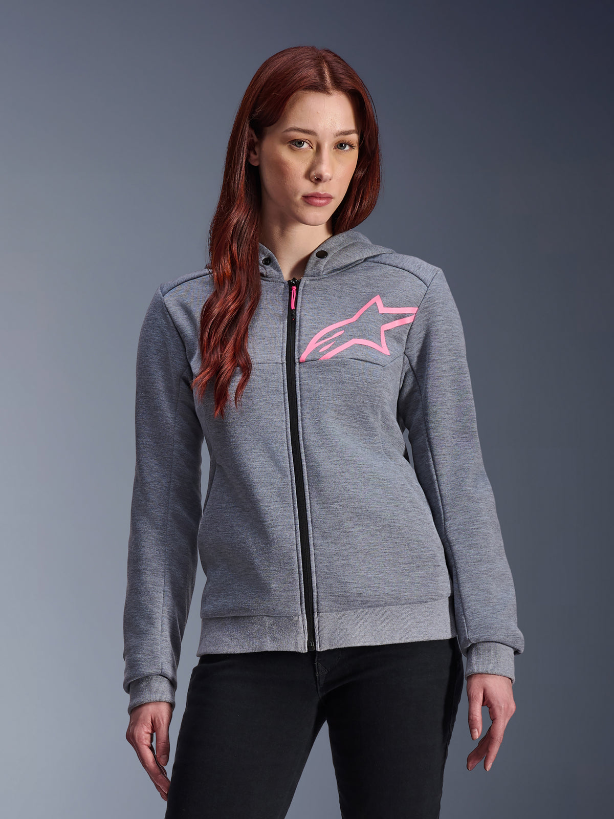 Alpinestars Stella Chrome V2 Sport Hoodie, Damen-Motorrad-Kapuzenjacke, Grau meliert mit pinkem Fluo-Stern-Logo, Tech-Fleece mit gerippten Bündchen und Saum, schwarzer Frontreißverschluss mit pinkem Zipper, lässige urbane Motorrad-Streetwear getragen mit schwarzer Hose