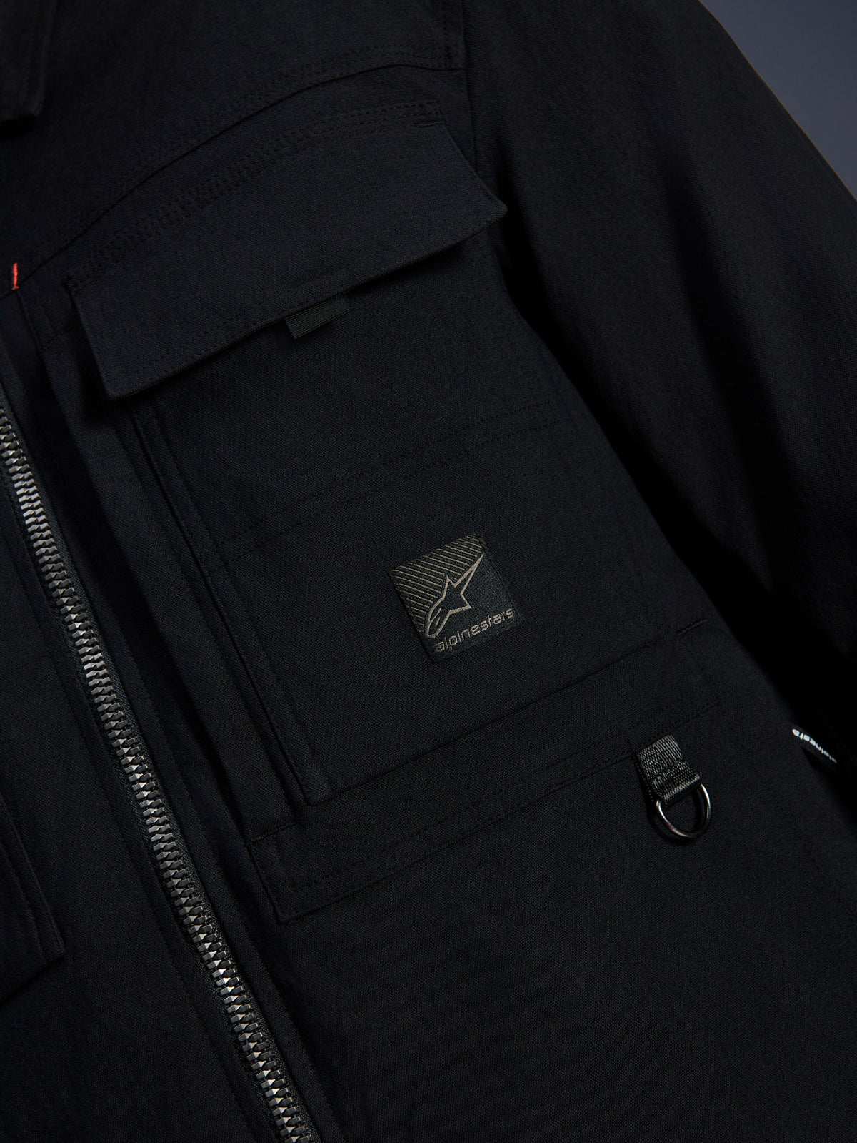 Alpinestars Bryon Water Resistant Overshirt, Schwarz, Nahaufnahme von gewachstem Canvas-Gewebe, Frontreißverschluss, Cargo-Brusttasche mit Alpinestars-Logo-Patch und Metall-D-Ring-Detail