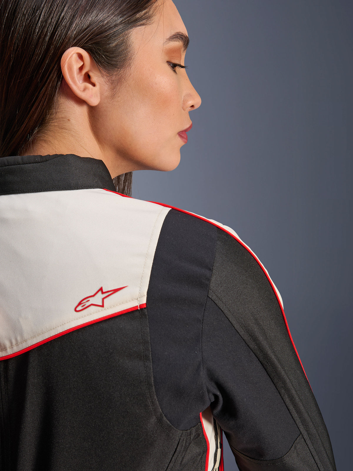 Alpinestars Stella T-Dyno WR Jacke in Schwarz Ecru Hellrot, Nahaufnahme von Schulter und Rücken mit ecrufarbenen Einsätzen, roten Paspeln und einem roten Alpinestars-Sternlogo, Textil-Motorradausrüstung für Damen