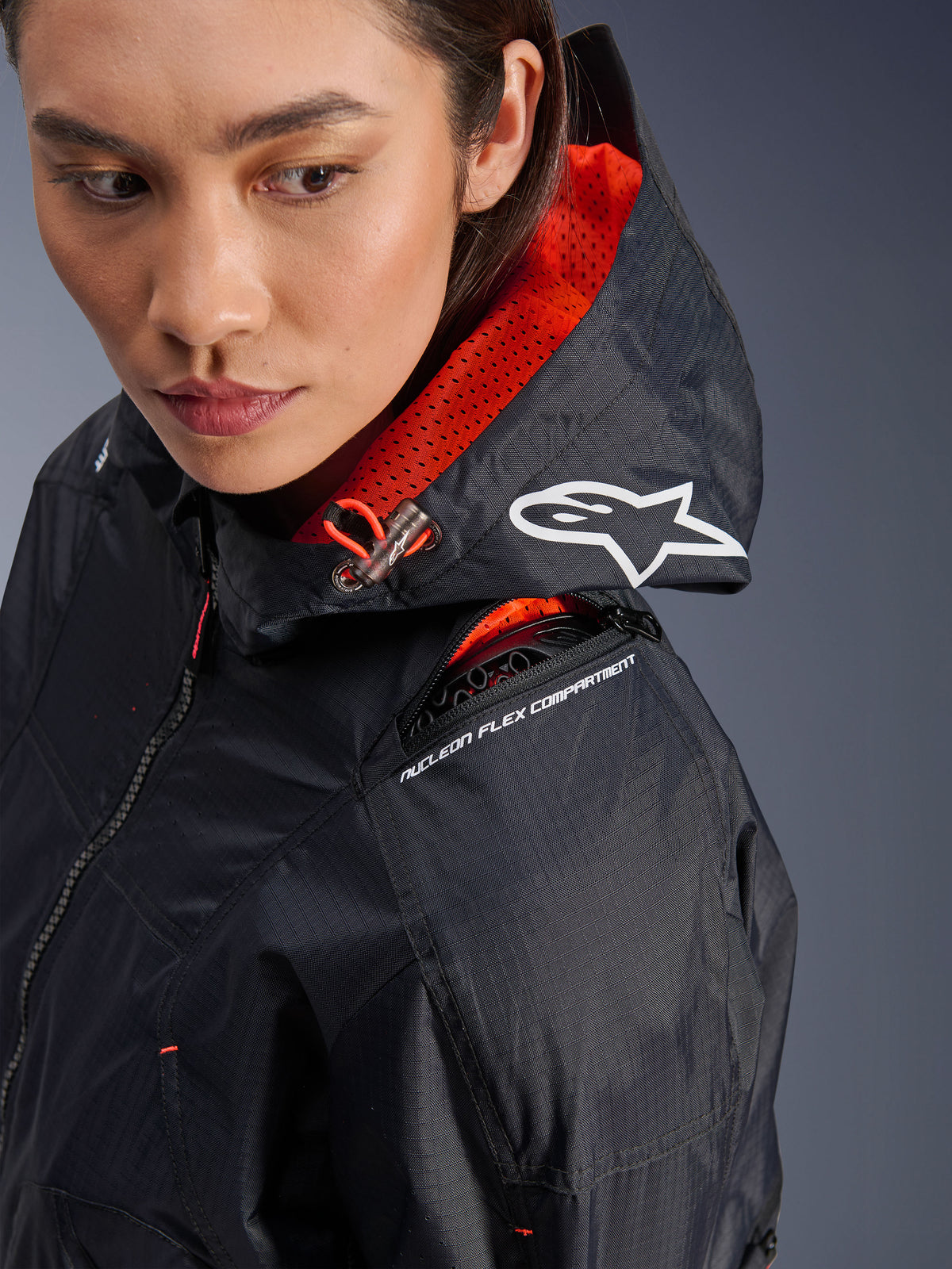 Alpinestars Molly Air Jacke, Motorradjacke für Damen, Schwarz und Fluo Coral, Nahaufnahme der Schulter mit Hervorhebung des Nucleon Flex Protektorenfachs und weißem Astars-Logo auf der Kapuze, urbane Fahrausrüstung aus Ripstop-Gewebe