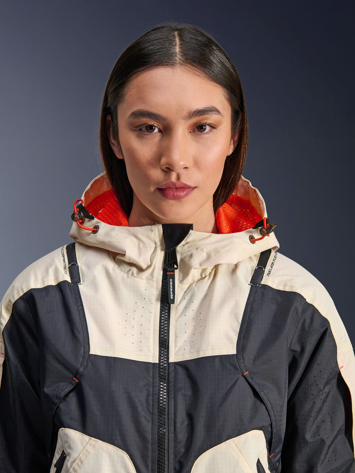 Alpinestars Molly Air Jacke, Damen-Textilmotorradjacke, Black Almond, Nahaufnahme der Vorderansicht eines Models in der Jacke mit cremefarbenem und schwarzem Panel-Design, Kapuze mit leuchtend orangem Mesh-Futter und laserperforierten Details auf der Brust