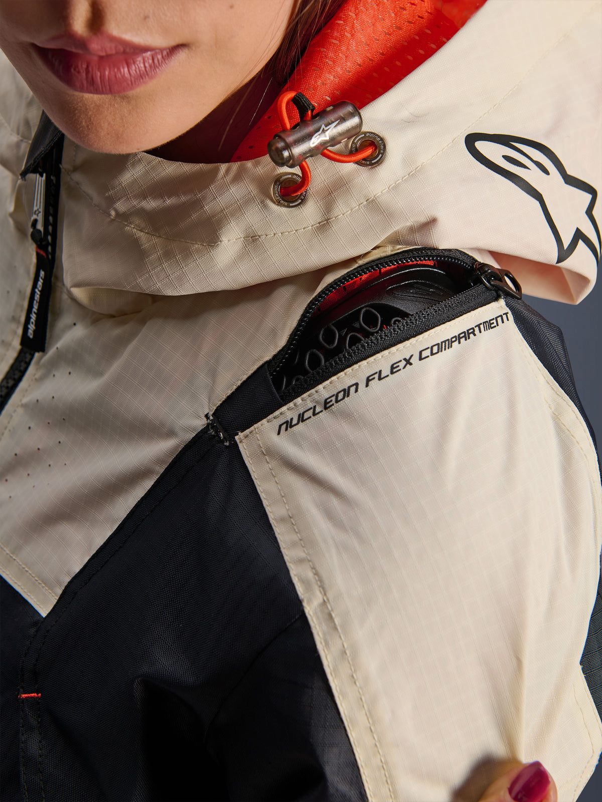 Alpinestars Molly Air Jacke, Motorradjacke für Damen, Black Almond, Nahaufnahme der Schulter mit dem Reißverschluss für das Nucleon Flex Compartment, Ripstop-Gewebe und orangefarbenem Mesh-Futter in der Kapuze