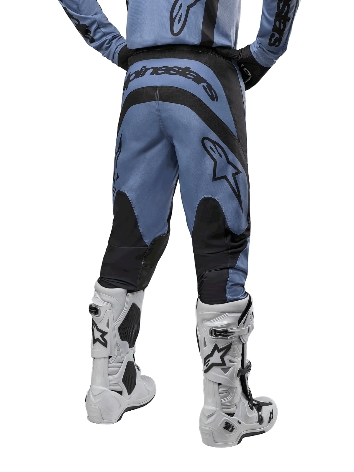 Alpinestars 2024 Fluid Lurv Hose, Motocross-Hose, Hellblau und Schwarz, Rückansicht mit schwarzen verstärkten Einsätzen und großem Markenlogo, kombiniert mit weiß-schwarzen Motocross-Stiefeln, professionelle Rennausrüstung für den Offroad-Einsatz