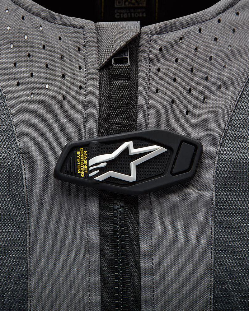 Alpinestars Tech-Air 5 Airbag-System, magnetische Verschlussklappe mit weißem Stern-Logo auf grauem perforiertem Gewebe.