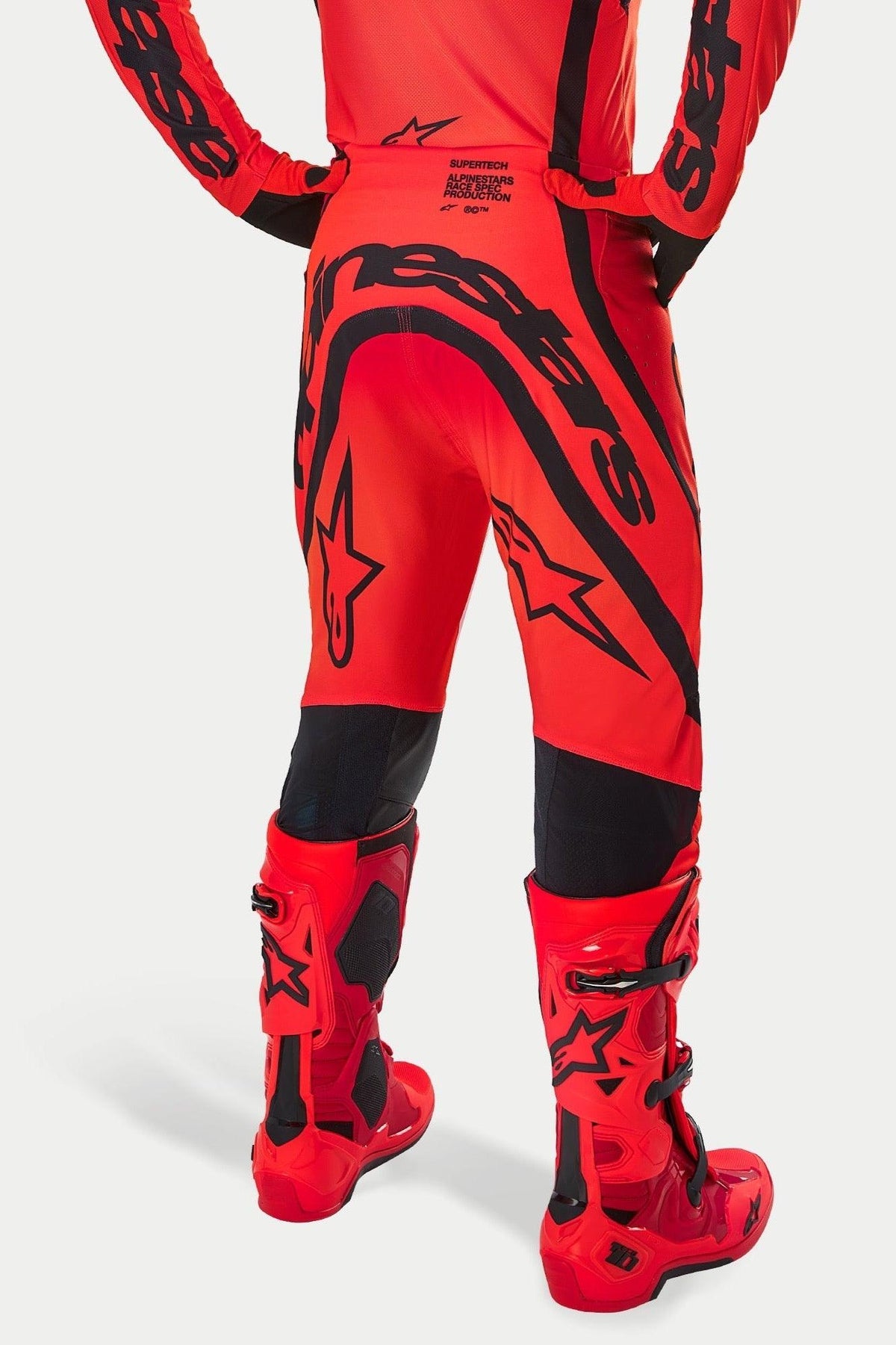 Alpinestars Supertech Ember LE Hose, Motocross-Hose, Fluo-Rot, Hellrot und Schwarz, Rückansicht mit großem schwarzem Branding am Gesäß und Stern-Logos, kombiniert mit passenden roten Motocross-Stiefeln, professionelle Rennausrüstung für Offroad-Performance