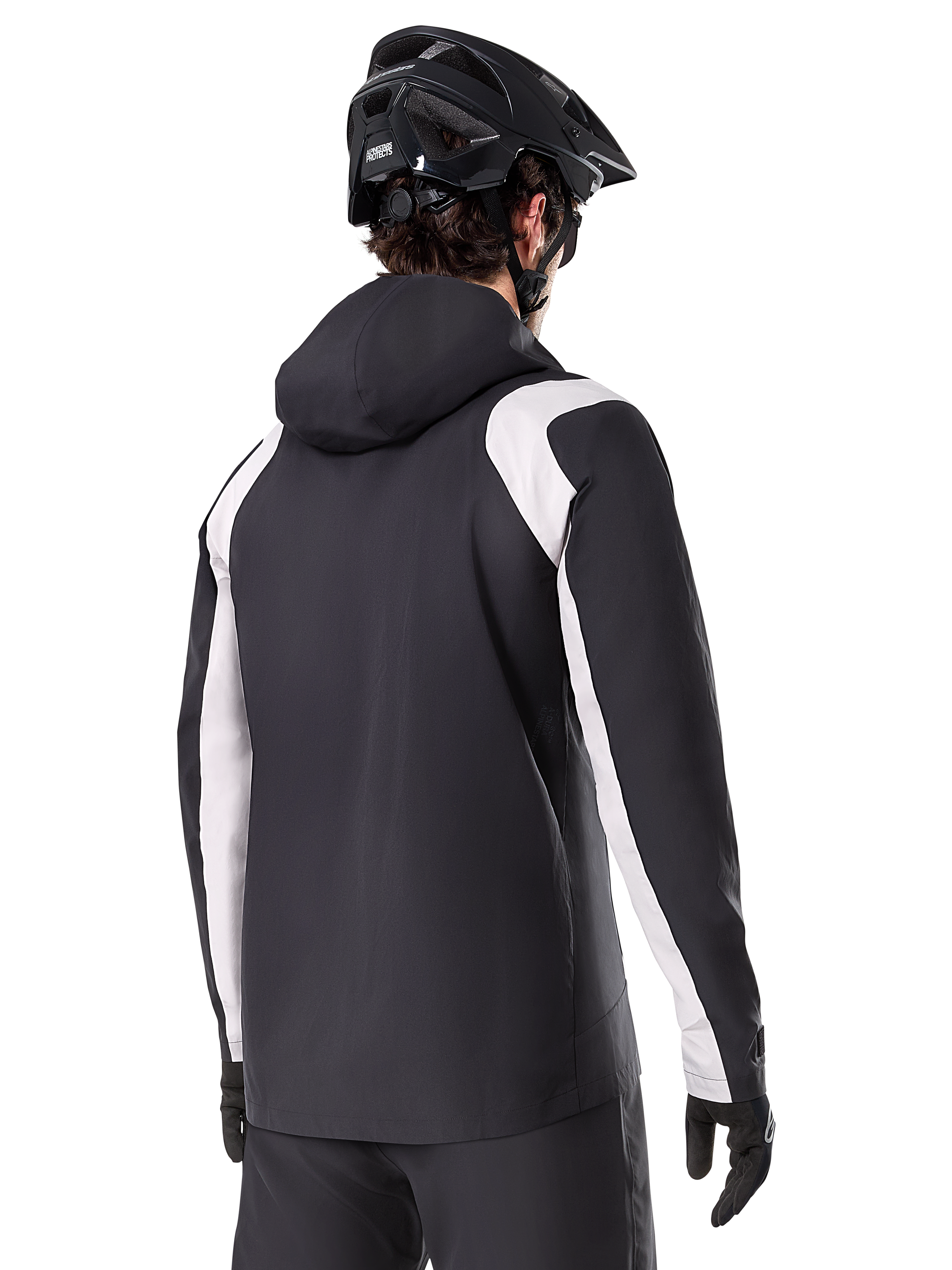 Alpinestars A-Dura Regenjacke, Mountainbike-Regenjacke, Schwarz mit weißen Ärmeleinsätzen, Rückansicht eines Fahrers mit schwarzem MTB-Helm und Handschuhen, technische wasserdichte 2,5-Lagen-Konstruktion, Mountainbike-Bekleidung