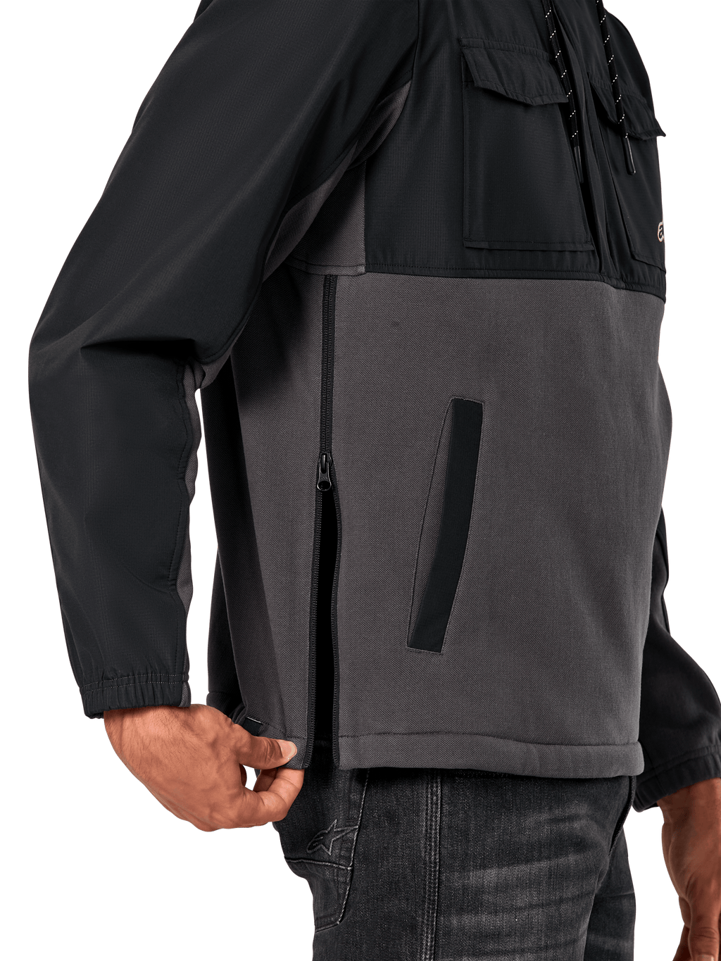Alpinestars Juncture Hybrid Jacke in Black Gunmetal, seitliche Detailansicht mit Fokus auf den seitlichen Reißverschluss und die untere Leistentasche, Materialmix-Design aus grauem Canvas-Fleece und schwarzen Ripstop-Overlays, lässige vom Motorsport inspirierte Streetwear