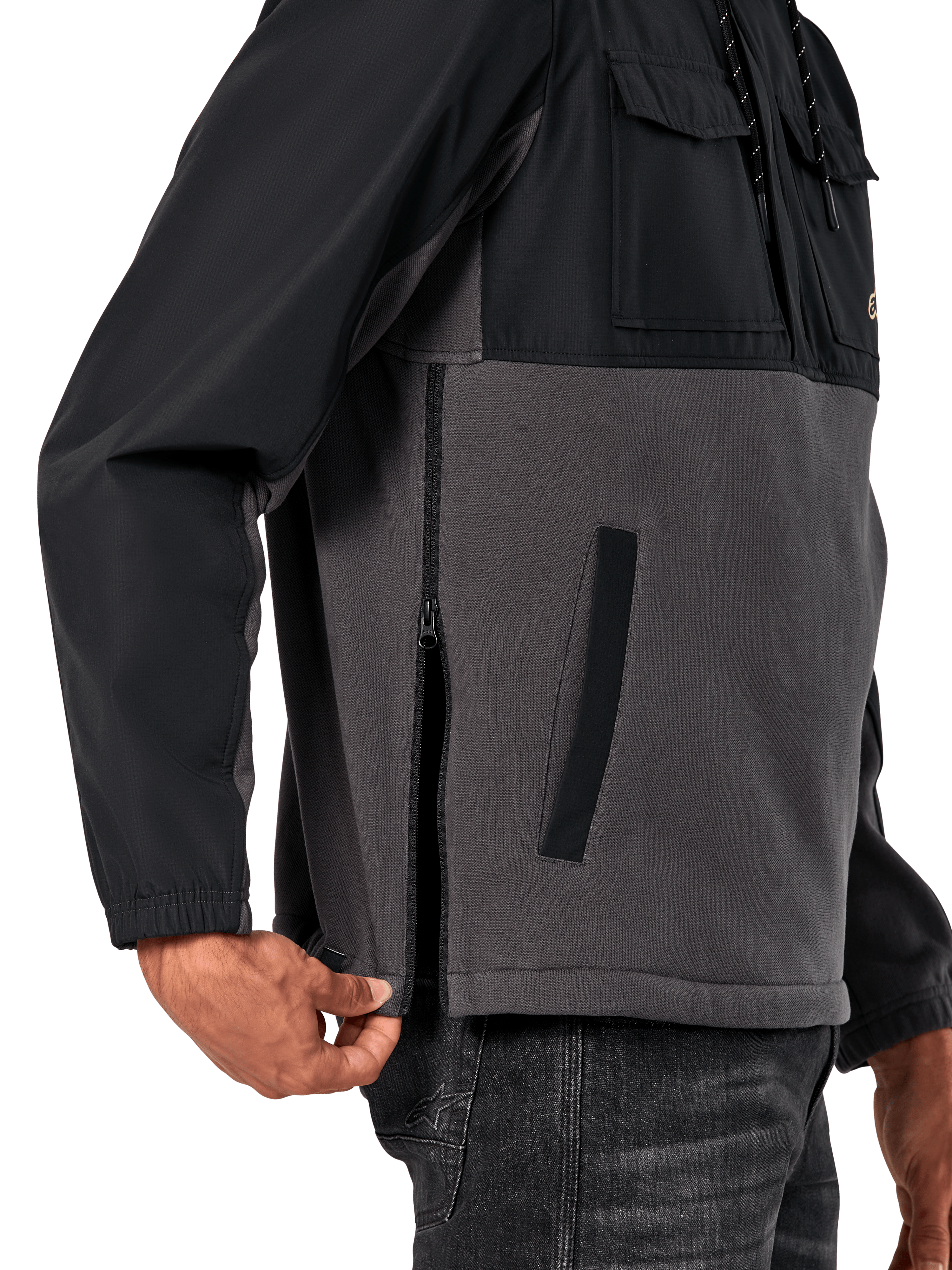 Alpinestars Juncture Hybrid Jacke in Black Gunmetal, seitliche Detailansicht mit Fokus auf den seitlichen Reißverschluss und die untere Leistentasche, Materialmix-Design aus grauem Canvas-Fleece und schwarzen Ripstop-Overlays, lässige vom Motorsport inspirierte Streetwear