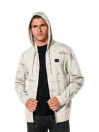 Alpinestars Plenitude Hoodie, lässige Sportbekleidung, Off-White Fleece mit Reißverschluss vorne und grauen Allover-Logo-Grafiken, getragen von einem Mann mit aufgesetzter Kapuze über einem schwarzen Shirt, kleiner Logo-Patch auf der Brust, Kängurutasche