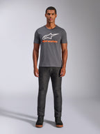 Alpinestars Always 2.0 CSF Tee, Kurzarm-T-Shirt, Anthrazitgrau mit weißem Logo und orangefarbenem Schriftzug, getragen von Model mit dunkler Jeans, lässige Motorsport-Streetwear
