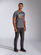 Alpinestars Always 2.0 CSF Tee, Kurzarm-T-Shirt, Anthrazitgrau, weißes A-Star-Logo mit orangefarbenem Branding, lässige Motorsport-Streetwear kombiniert mit dunkler Jeans und schwarzen Sneakern