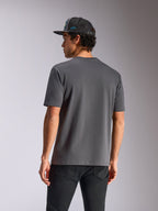 Alpinestars Blaze 2.0 CSF Tee, kurzärmeliges T-Shirt, Anthrazitgrau, Rückansicht, getragen mit schwarzen Jeans und einer Mesh-Cap, lässige, vom Motorsport inspirierte Streetwear