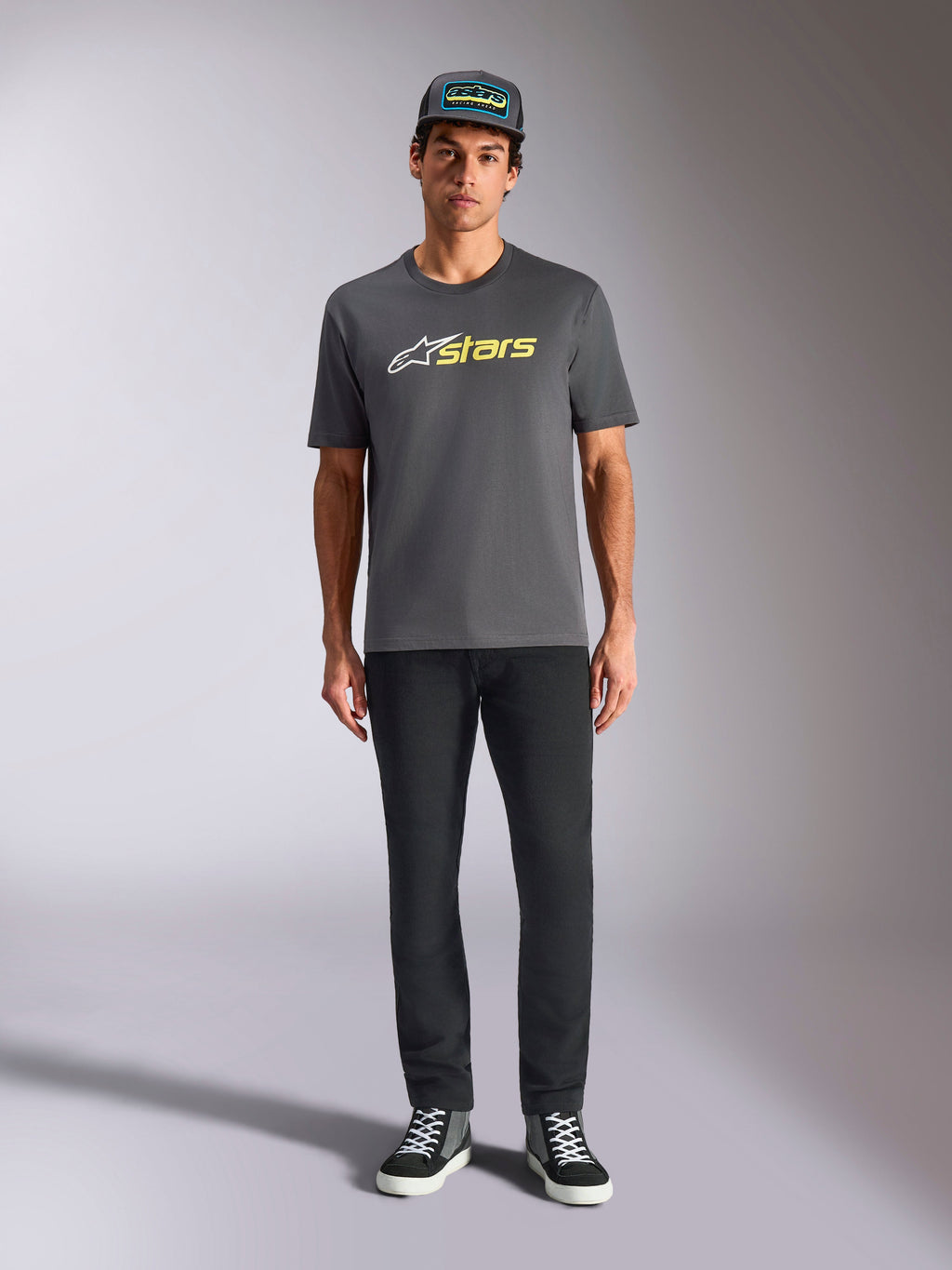 Alpinestars Blaze 2.0 CSF Tee, Kurzarm-T-Shirt, Anthrazitgrau mit weißem und Hi-Vis gelbem Logo, kombiniert mit schwarzer Hose und passender Trucker-Cap, lässiger Motorsport-Lifestyle