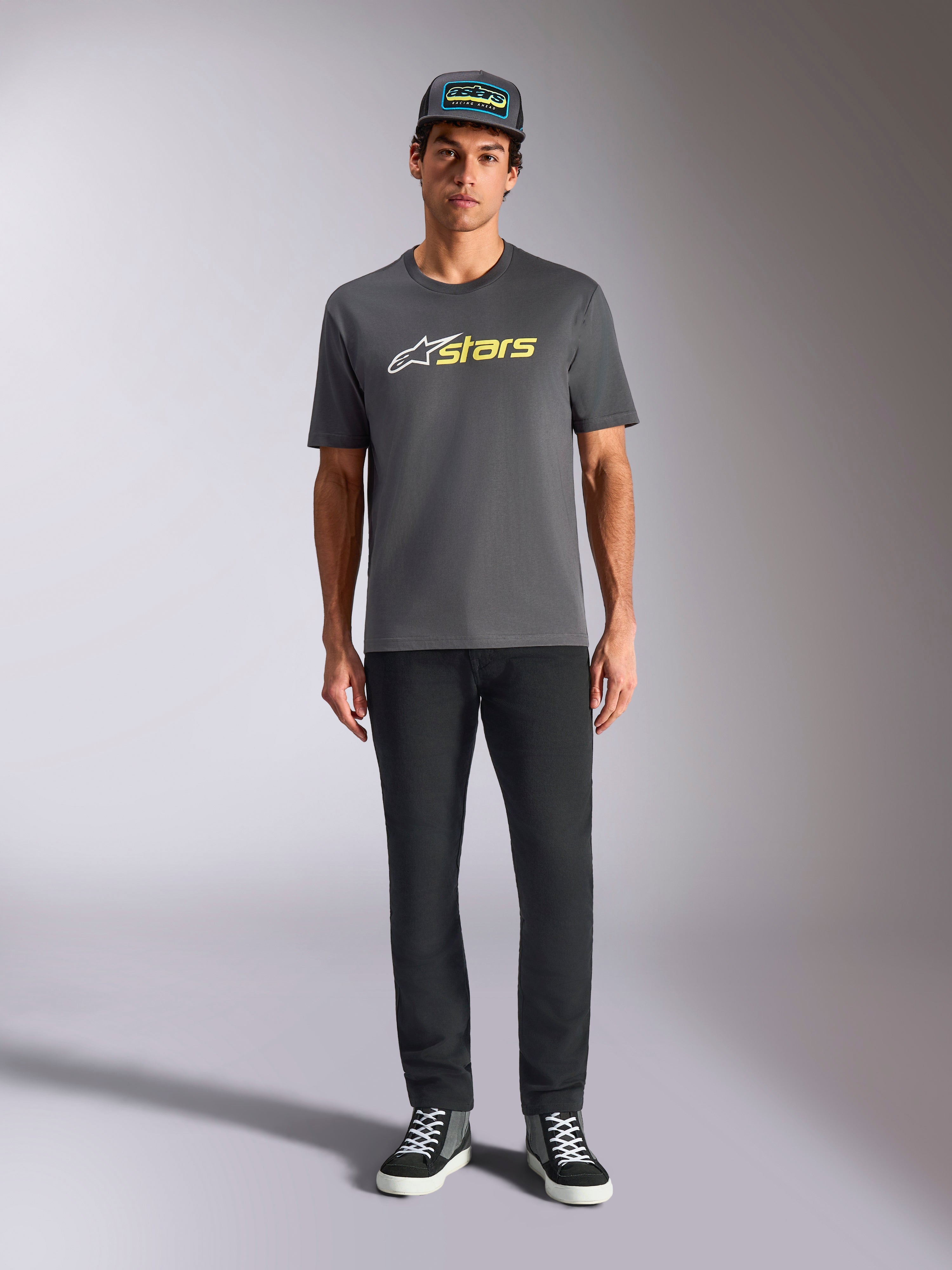 Alpinestars Blaze 2.0 CSF Tee, Kurzarm-T-Shirt, Anthrazitgrau mit weißem und Hi-Vis gelbem Logo, kombiniert mit schwarzer Hose und passender Trucker-Cap, lässiger Motorsport-Lifestyle