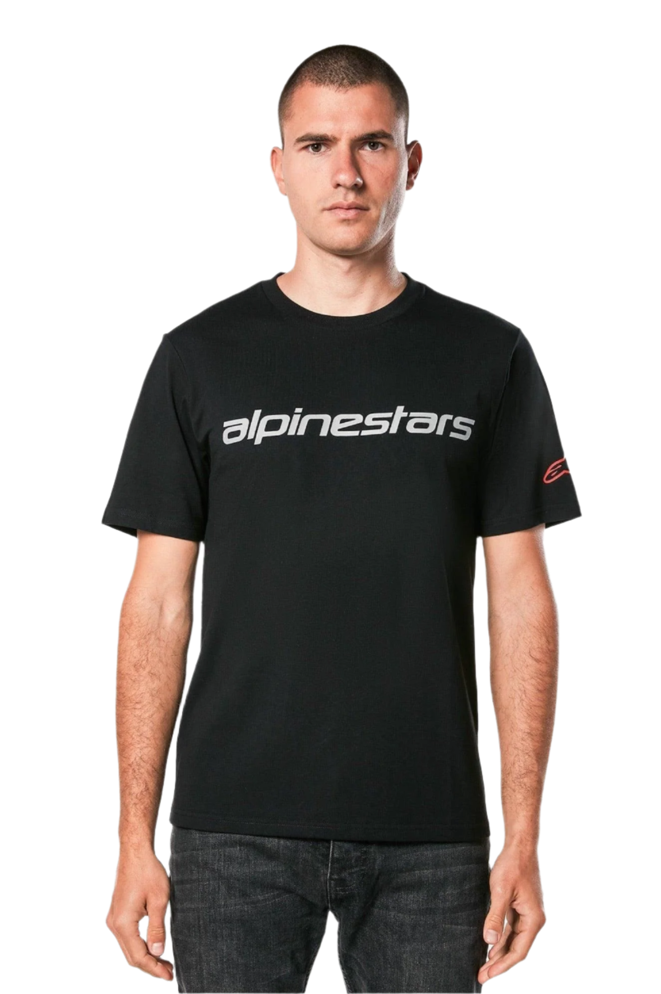 Alpinestars Linear Wordmark 2.0 CSF Tee, kurzärmeliges T-Shirt, Schwarz, graue Linear-Wortmarke auf der Brust und rotes Ageless-Logo am Ärmel, getragen von einem Model mit dunkler Jeans, lässige vom Motorsport inspirierte Streetwear