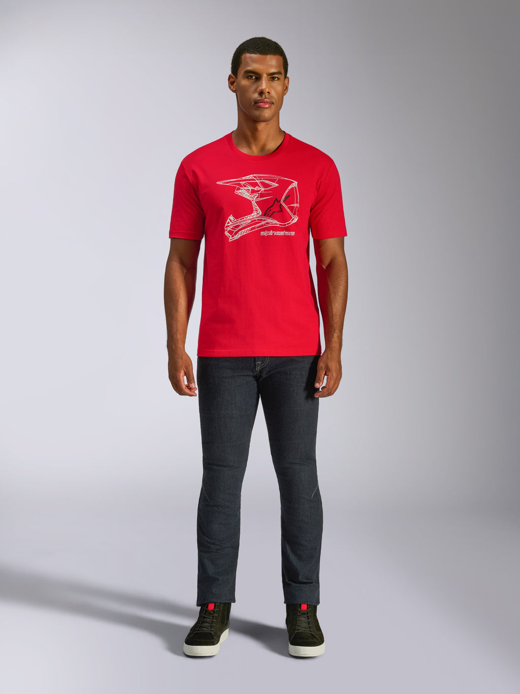 Alpinestars MX Helmet CSF Tee, kurzärmeliges T-Shirt, Rot, weiße MX-Helm-Grafik, lässige Motorsport-Sportbekleidung, getragen mit dunkler Jeans und Sneakern
