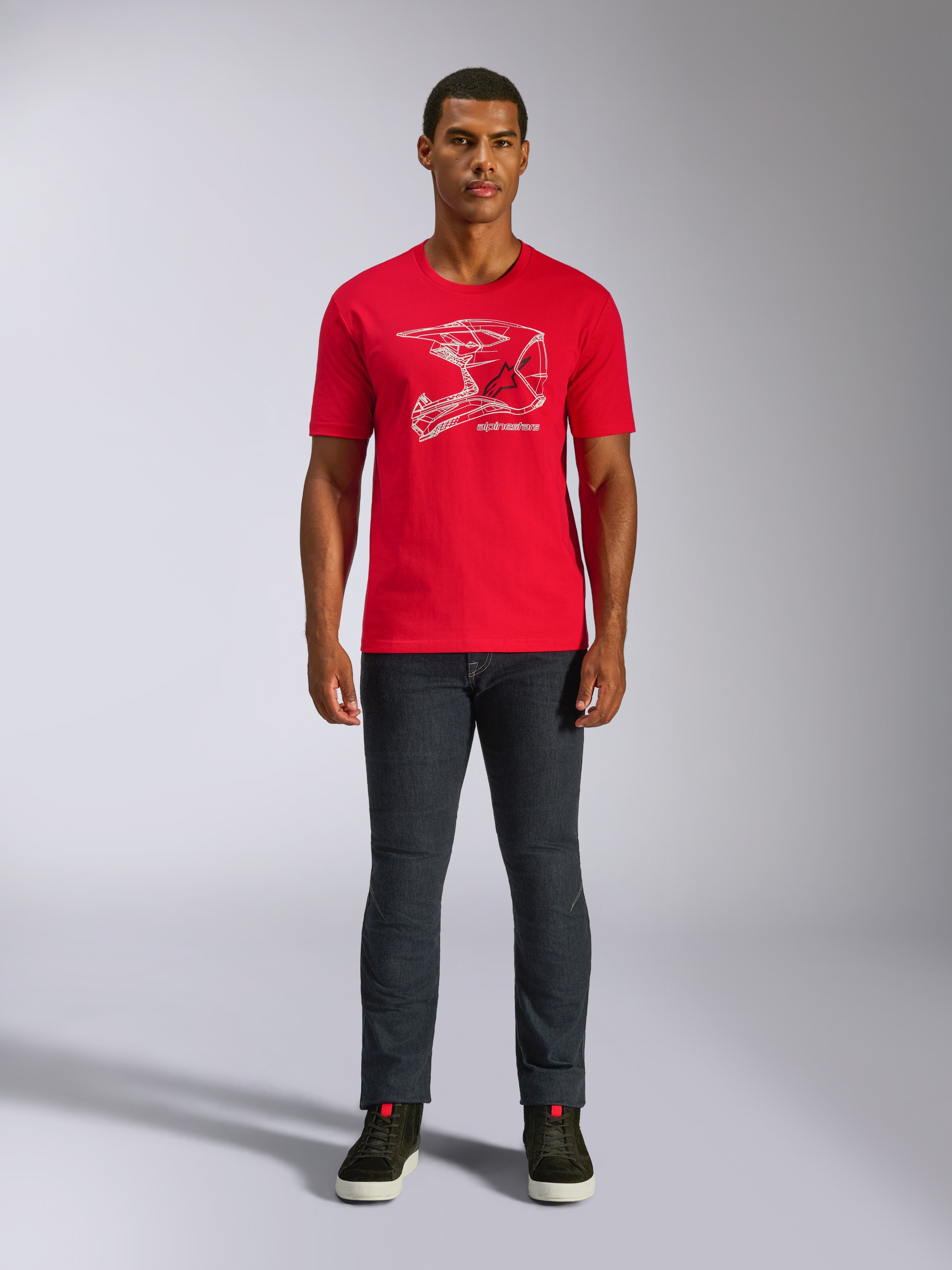 Alpinestars MX Helmet CSF Tee, kurzärmeliges T-Shirt, Rot, weiße MX-Helm-Grafik, lässige Motorsport-Sportbekleidung, getragen mit dunkler Jeans und Sneakern