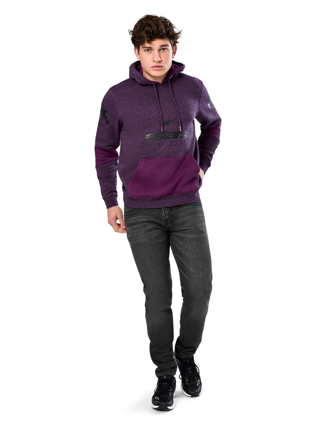 Alpinestars Perpetuate Hoodie, lässige Streetwear, lila meliertes Fleece mit dunkelvioletten Stoffbahnen an Kängurutasche und Ärmeln, schwarzes Brust-Logo, Kapuze mit Kordelzug, getragen von einem Model mit dunkelgrauen Jeans und schwarzen Sneakern