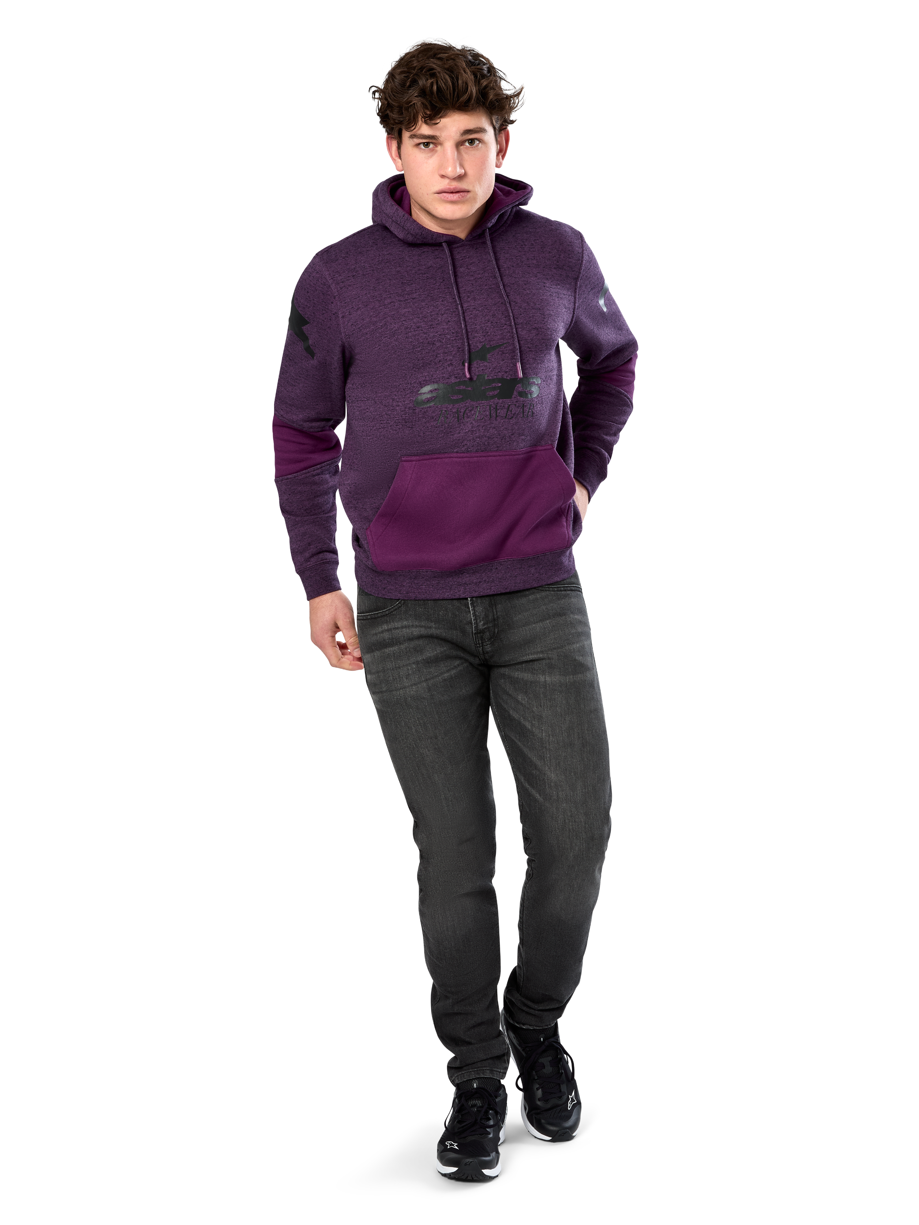 Alpinestars Perpetuate Hoodie, lässige Streetwear, lila meliertes Fleece mit dunkelvioletten Stoffbahnen an Kängurutasche und Ärmeln, schwarzes Brust-Logo, Kapuze mit Kordelzug, getragen von einem Model mit dunkelgrauen Jeans und schwarzen Sneakern