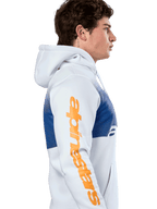 Alpinestars Specter Hoodie, lässige Streetwear, Weiß mit blauem Farbverlauf-Druck, große orangefarbene Alpinestars Wortmarke auf dem Ärmel, Seitenprofil eines Mannes, der den Kapuzenpullover trägt