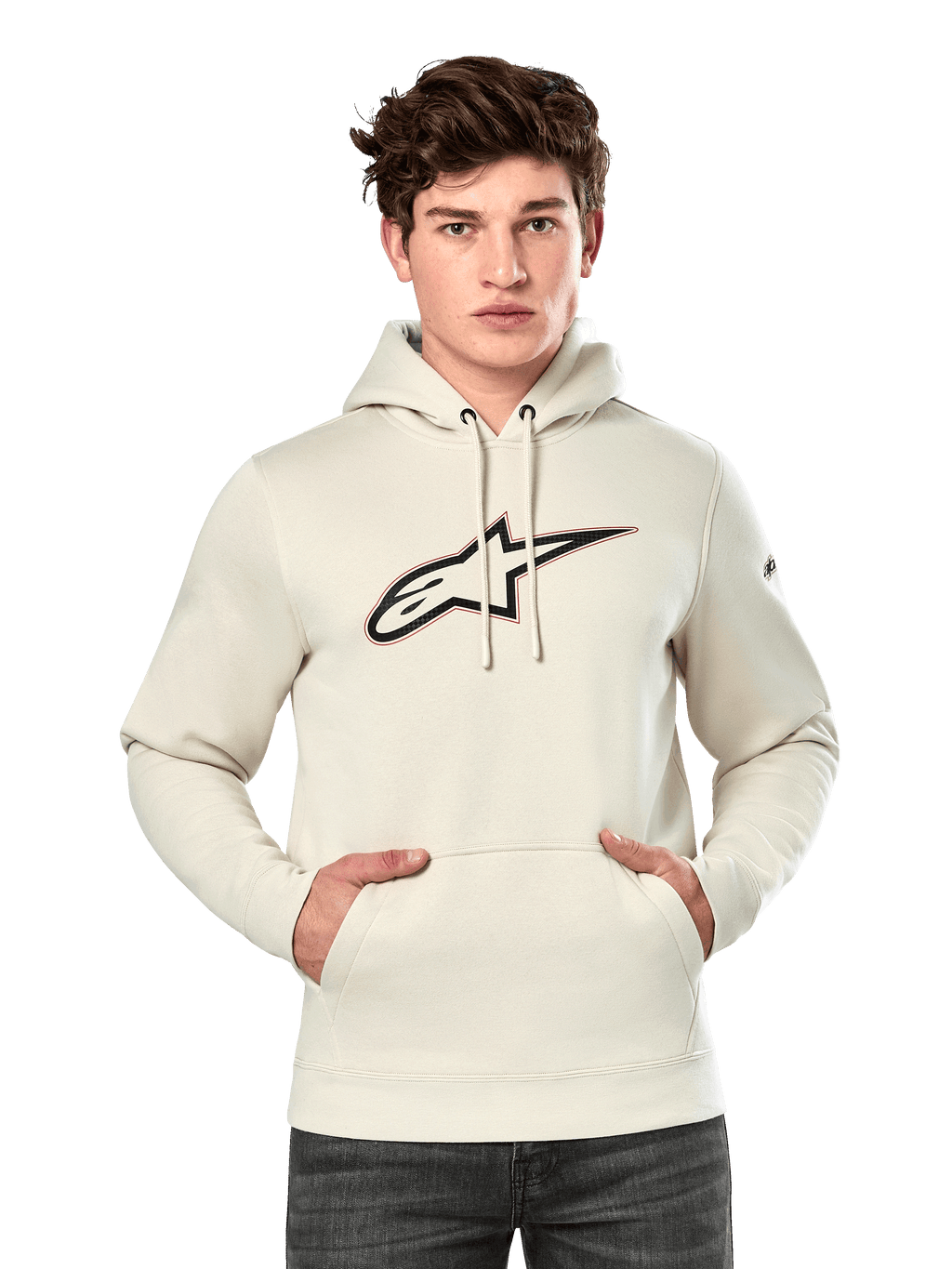 Alpinestars Insignia Hoodie, hellbeiger Fleece-Hoodie, männliches Model trägt Kapuzenpullover mit großem Alpinestars-Logo in Carbonfaser-Optik und roter Umrandung auf der Brust, Kängurutasche, Kapuze mit Kordelzug, lässige vom Motorsport inspirierte Streetwear