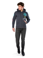 Alpinestars Variegate Hoodie, Fleece-Hoodie mit Reißverschluss, Gunmetal-Grau, getragen von einem Modell mit schwarzen Jeans und Sneakern, mit türkisfarbenem 'ASTARS'-Branding und bunten Logo-Grafiken auf Ärmeln und Brust, lässige Motorsport-Streetwear