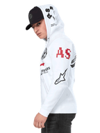 Alpinestars Variegate Hoodie, weißer Fleece-Hoodie mit Frontreißverschluss, Multi-Logo-Grafiken an den Ärmeln und der Kapuze mit rotem „AS“-Schriftzug und schwarzem Stern-Logo, getragen von einem Mann mit schwarzer Kappe, lässige Motorsport-Streetwear