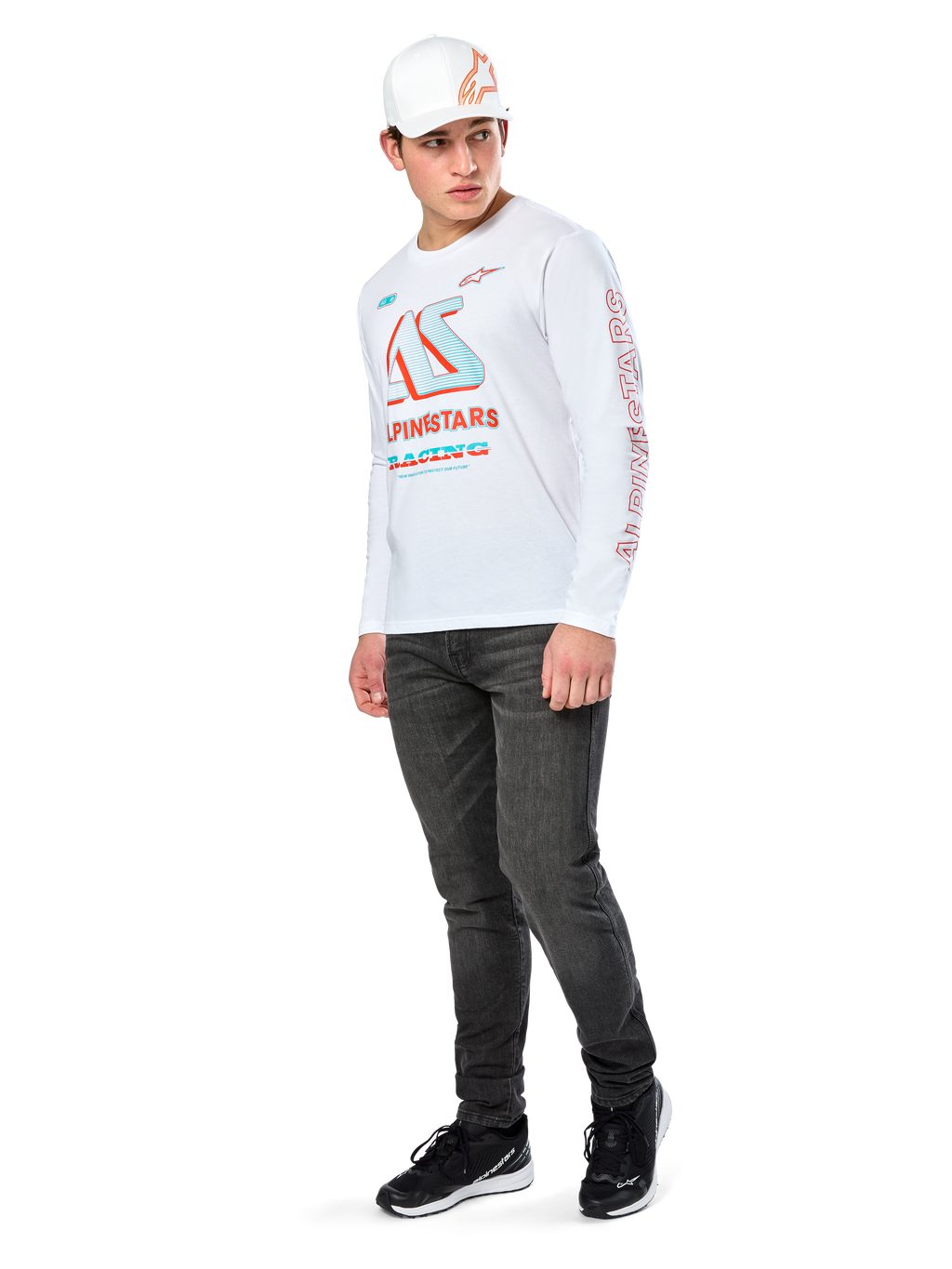 Alpinestars Ayess CSF Tee, Langarm-T-Shirt, Weiß, mit großen blauen und roten CSF-Racing-Grafiken auf der Brust und rotem Alpinestars-Branding am Ärmel, getragen mit dunkler Jeans und einer weißen Alpinestars-Kappe, lässige Motorsport-Streetwear