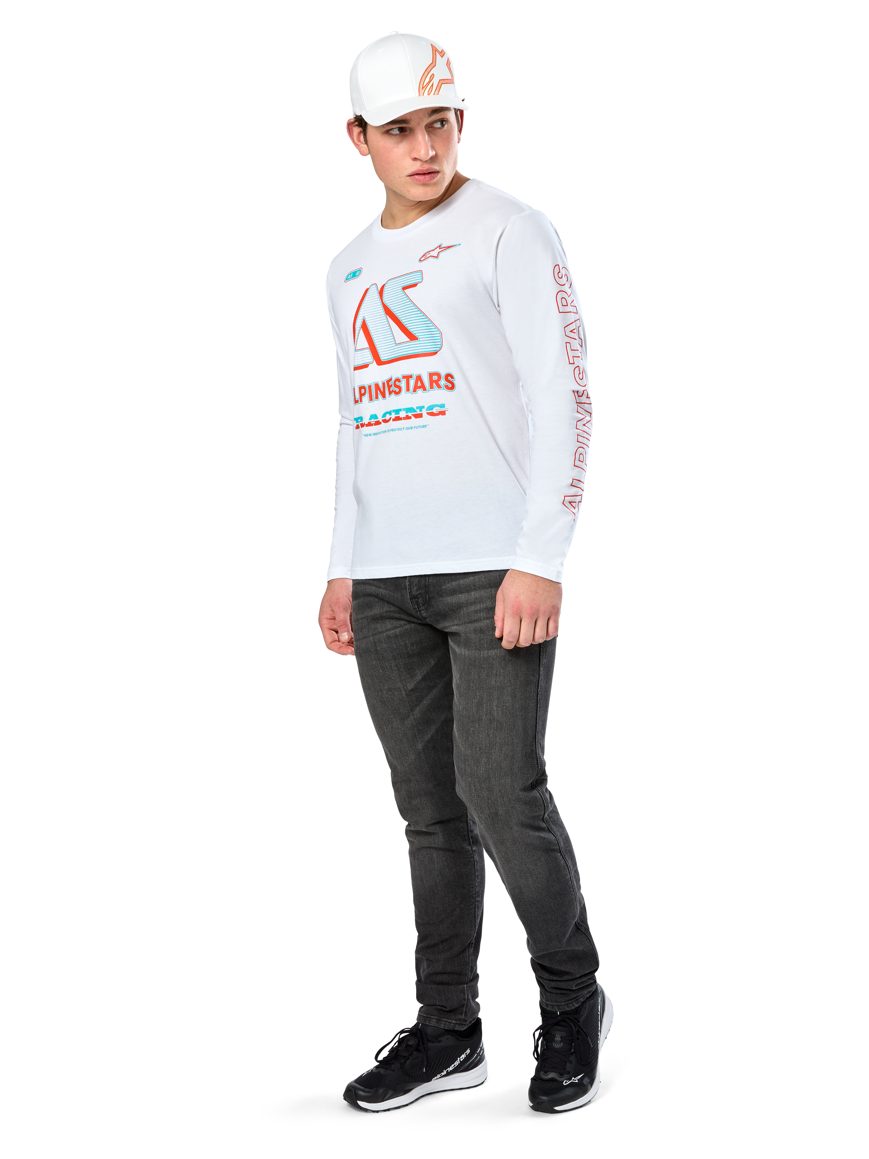 Alpinestars Ayess CSF Tee, Langarm-T-Shirt, Weiß, mit großen blauen und roten CSF-Racing-Grafiken auf der Brust und rotem Alpinestars-Branding am Ärmel, getragen mit dunkler Jeans und einer weißen Alpinestars-Kappe, lässige Motorsport-Streetwear